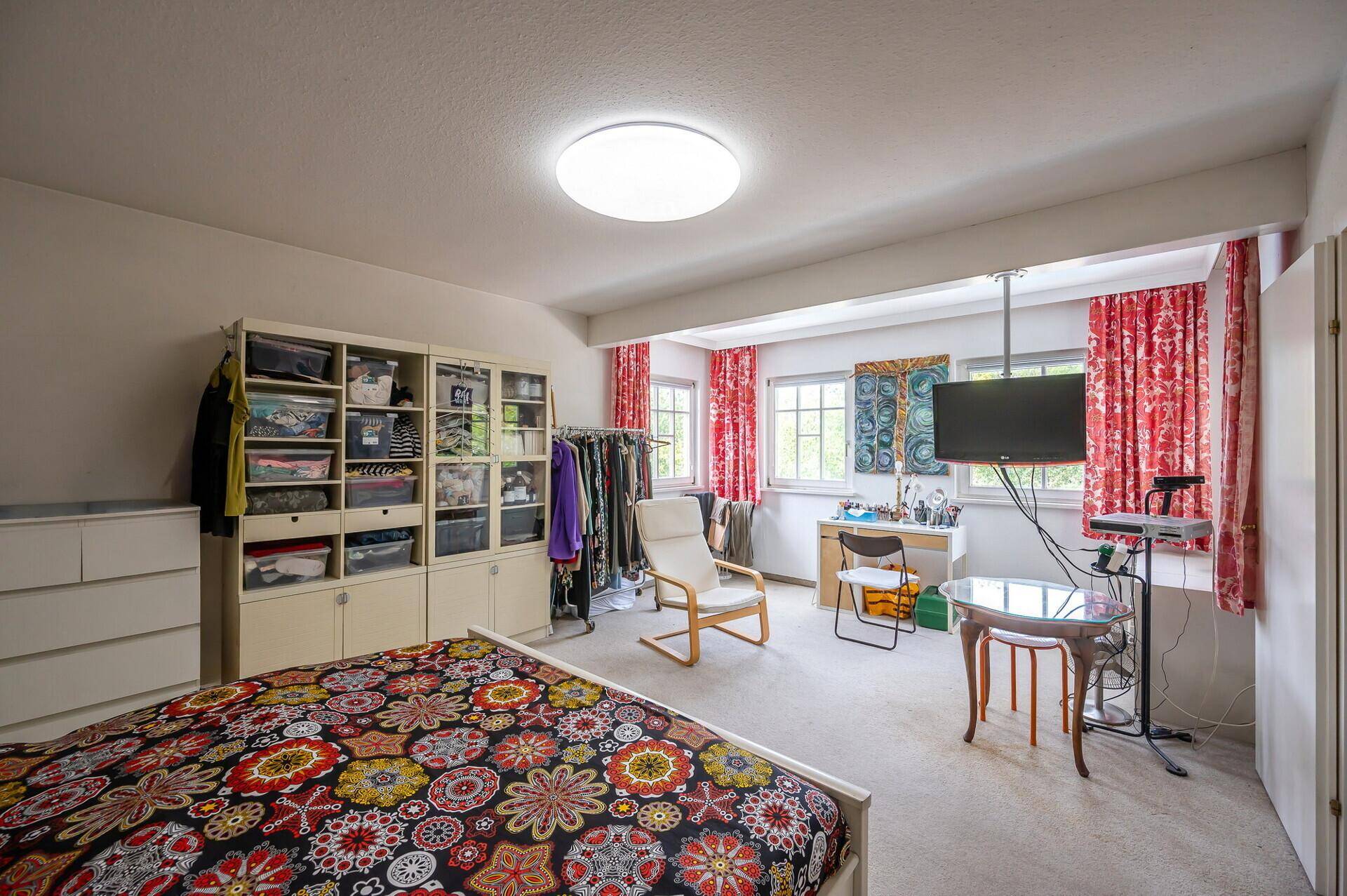 Geräumiges Schlafzimmer mit Doppelbett, Kleiderschrank und Fernseher.
