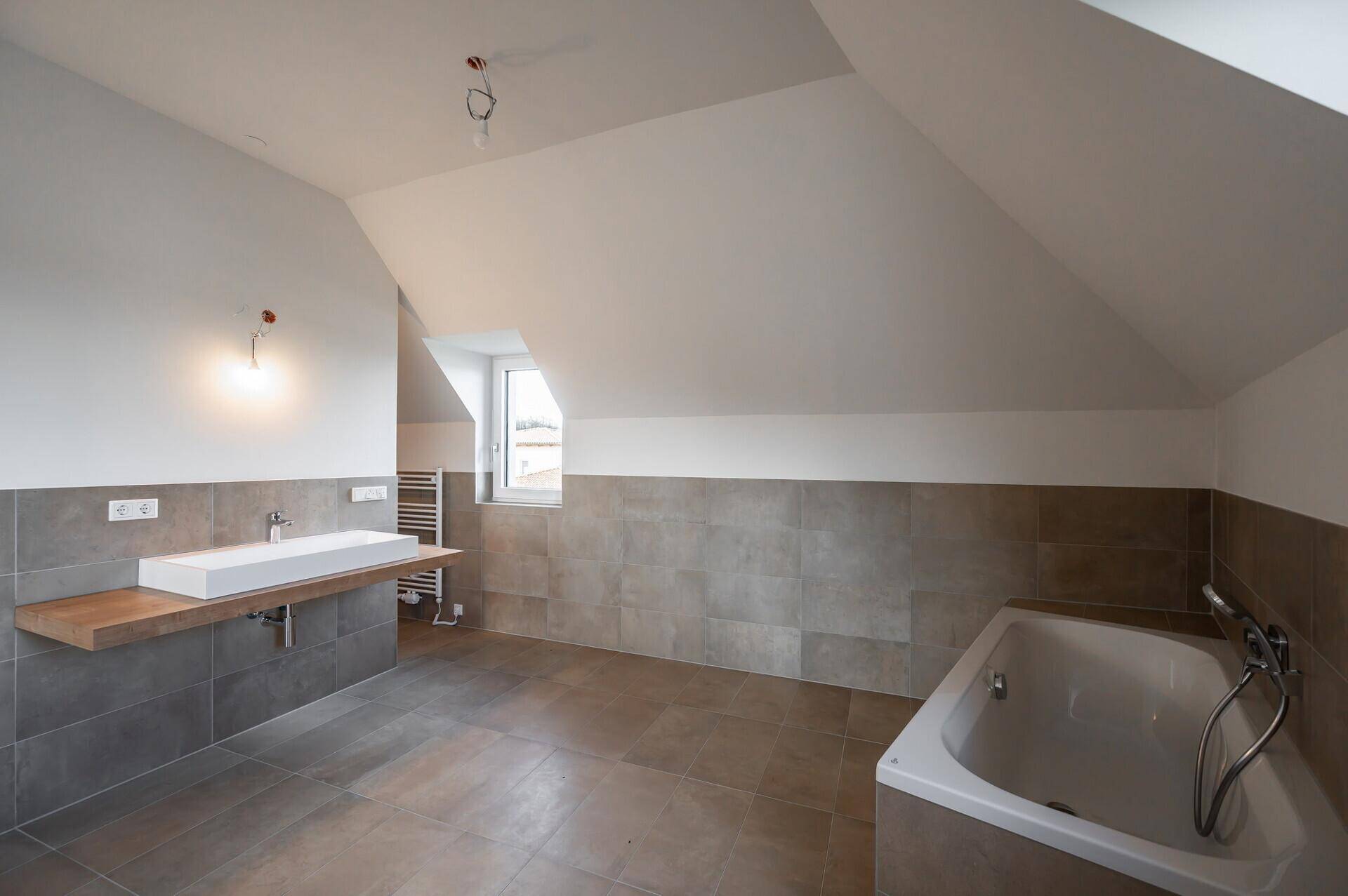 Geräumiges Badezimmer im Dachgeschoss mit Badewanne, Einzelwaschbecken und Dachfenster.