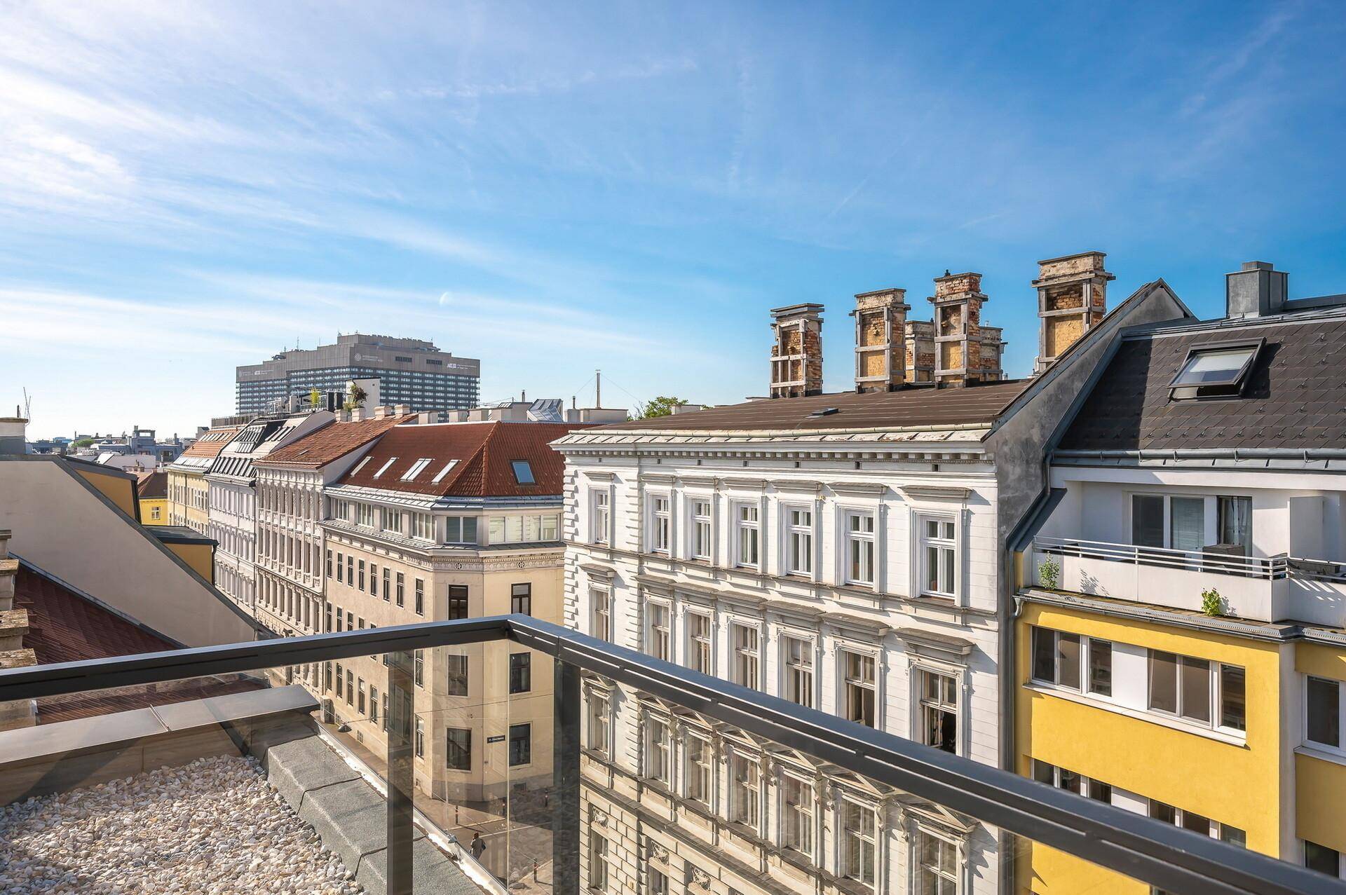 Weitläufiger Stadtblick von einer oberen Etage mit historischen Gebäuden und Dächern.