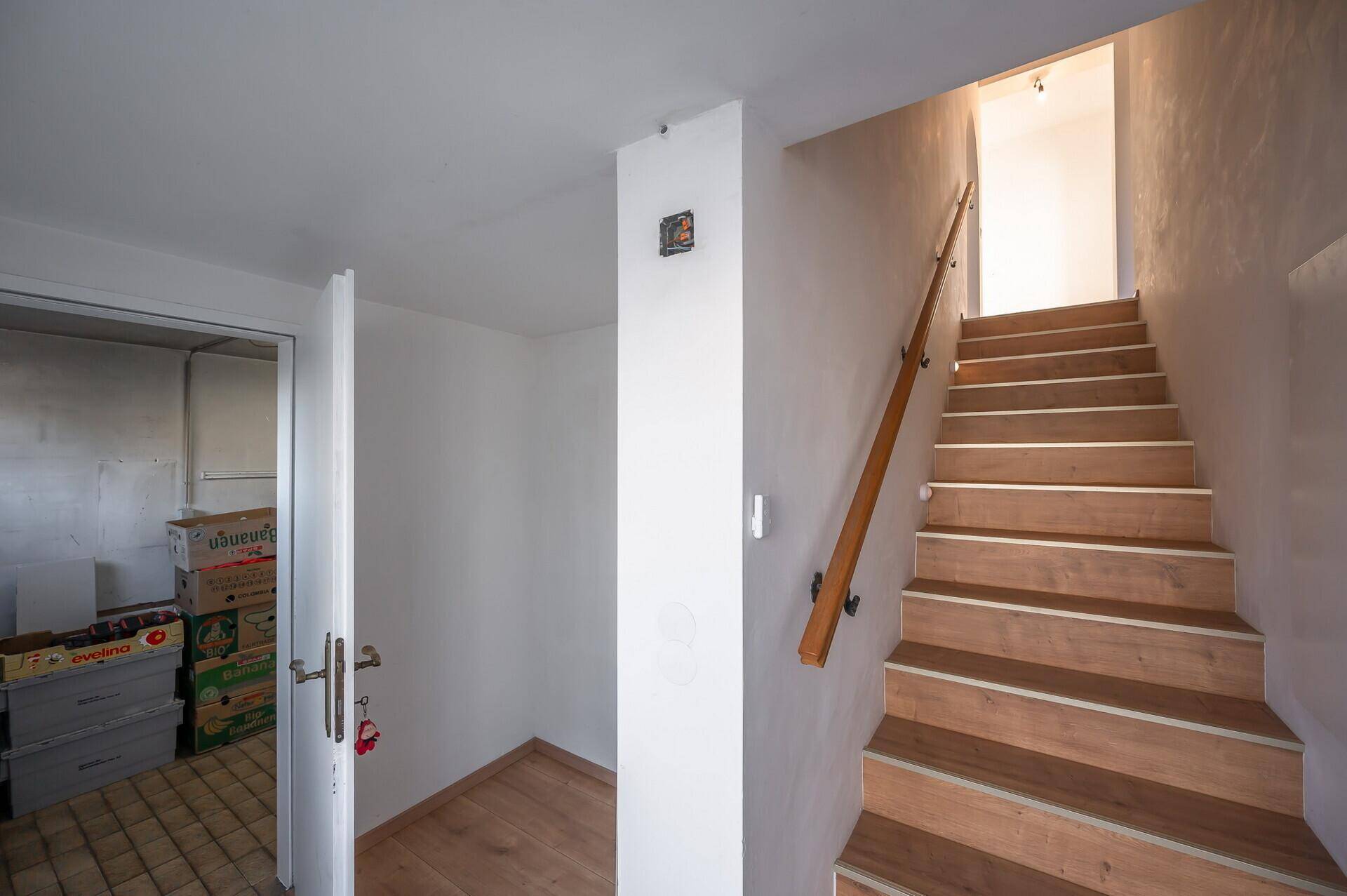 Flur mit Holztreppe ins Obergeschoss und Zugang zu einem praktischen Abstellraum.
