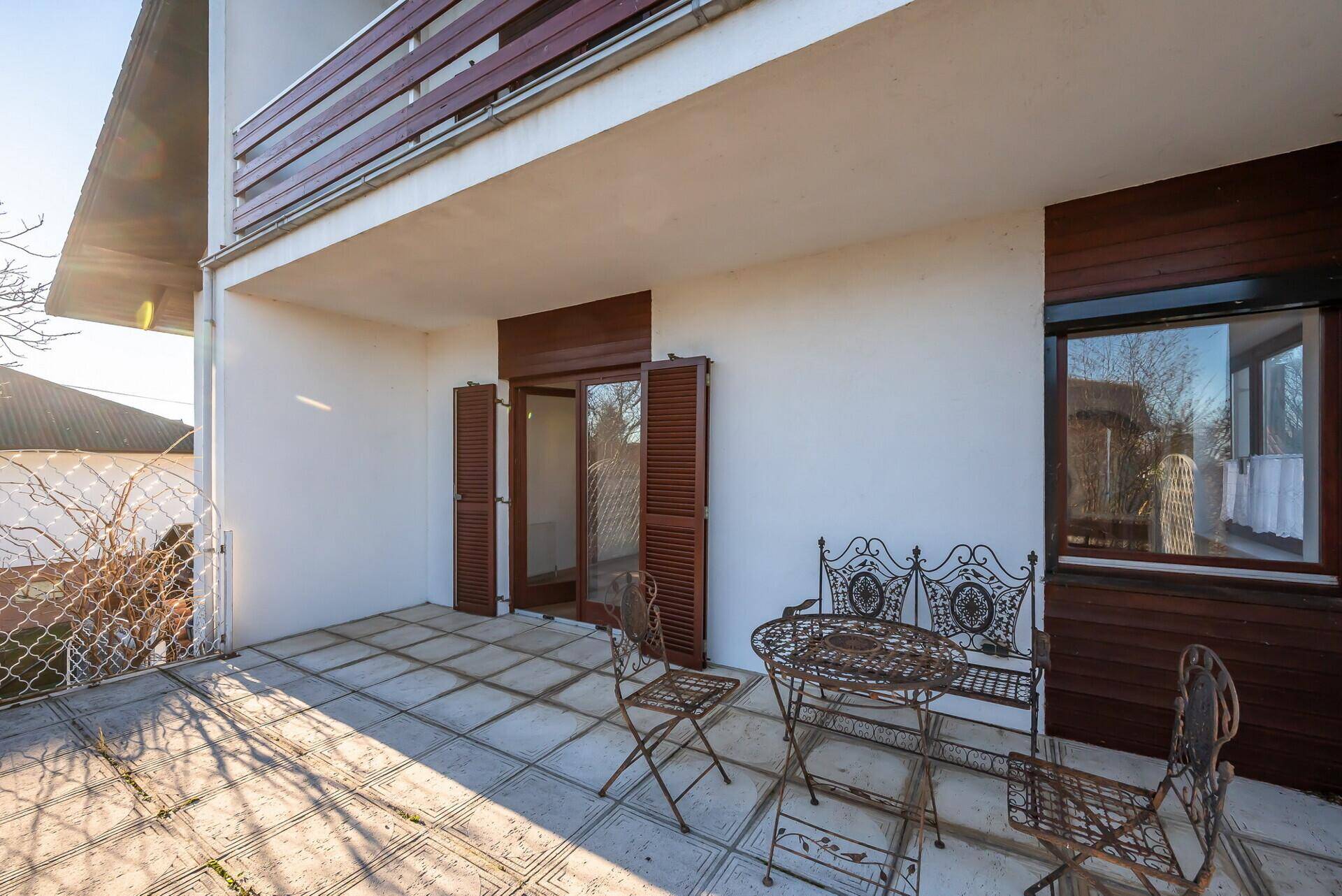 Geflieste Terrasse mit Gartenmöbeln, direkt vom Haus aus durch Doppeltüren zugänglich.