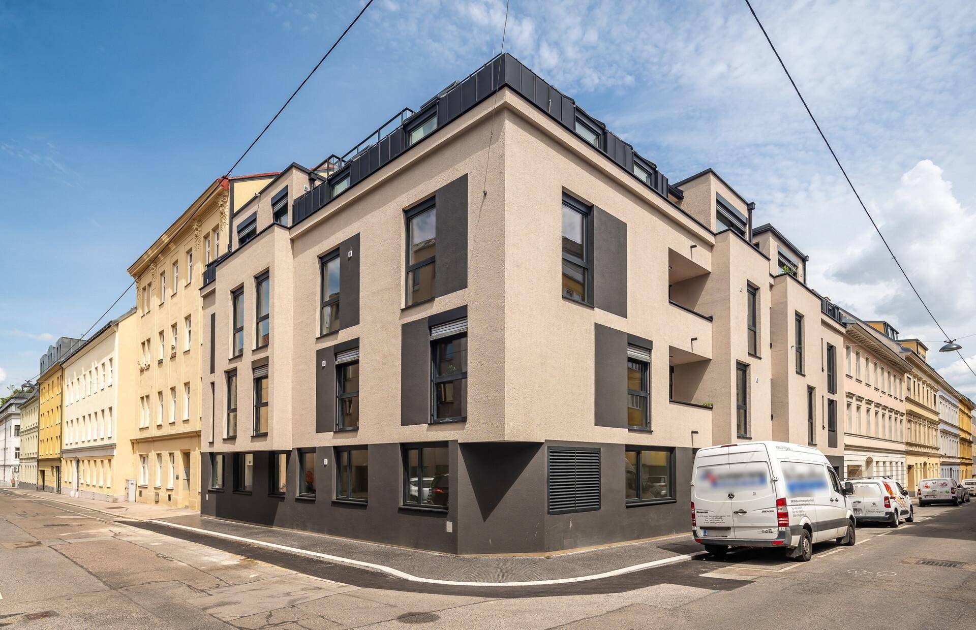 Moderne Gebäudefassade an einer Straßenecke mit klaren Linien und großen Fenstern.