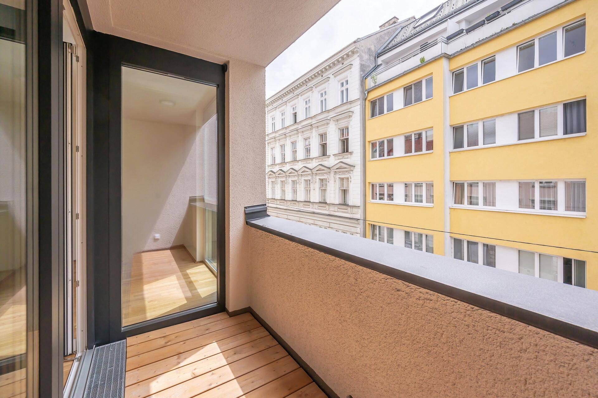 Kleiner Balkon mit Holzboden und Blick auf die umliegenden Stadtgebäude.