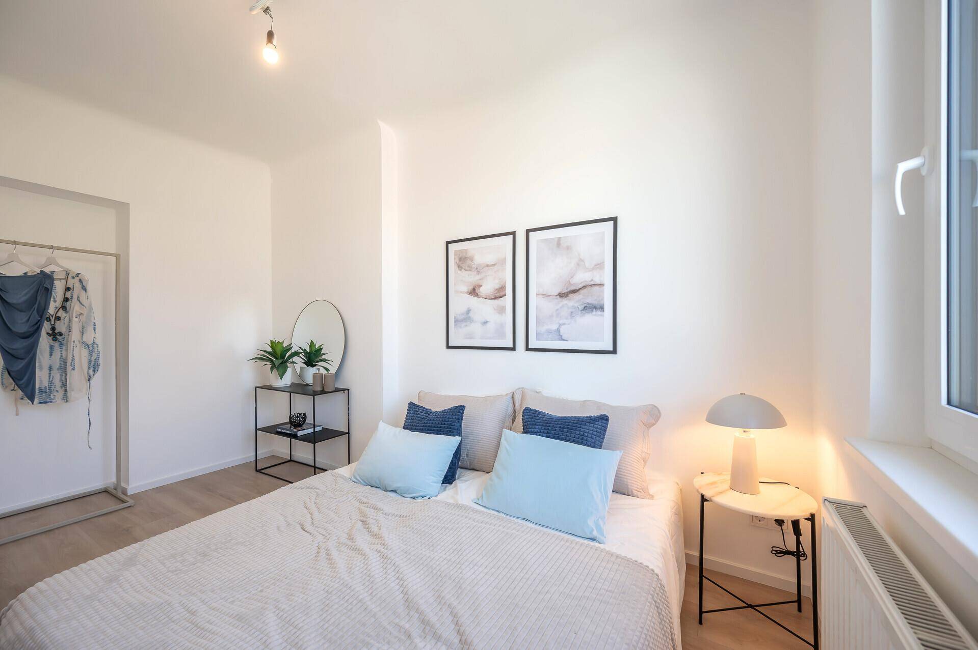 Helles Schlafzimmer mit Doppelbett, Fenster und minimalistischer Einrichtung.