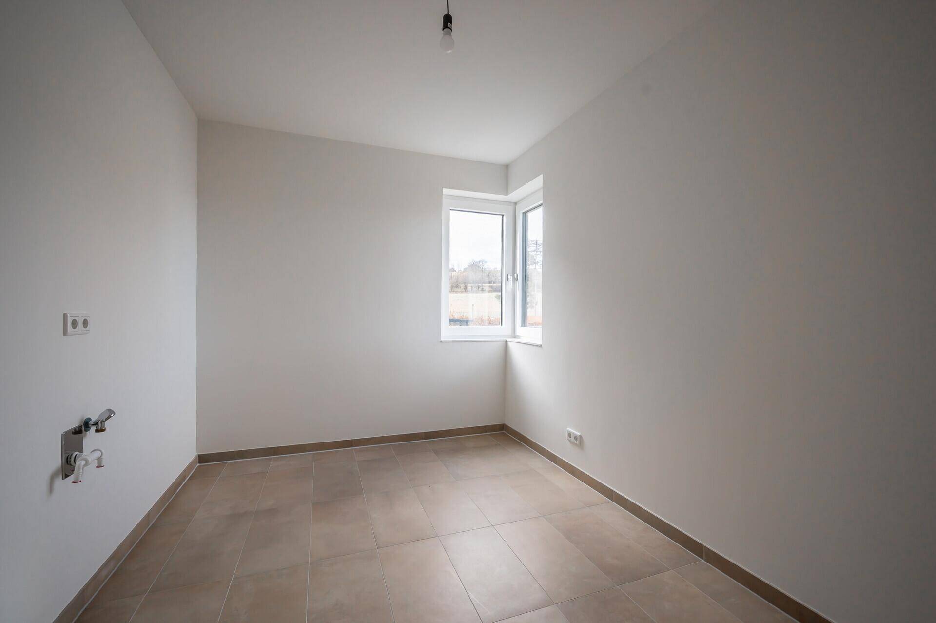 Kleiner Raum mit Fliesenboden und Fenster, ideal als Abstellraum nutzbar.