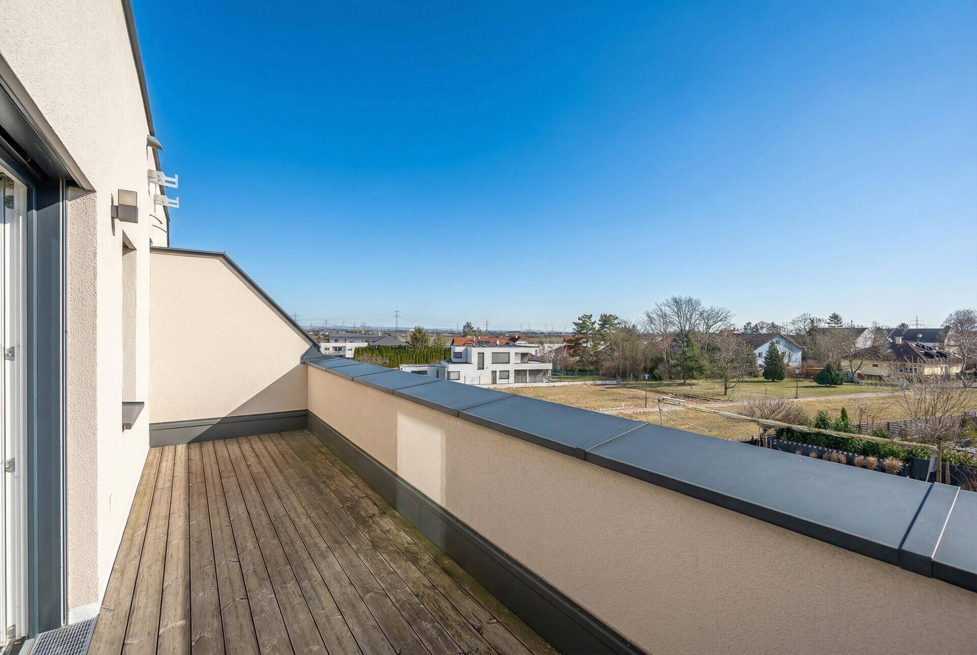 Geräumige Dachterrasse mit Holzboden und weitem Blick über die Umgebung.