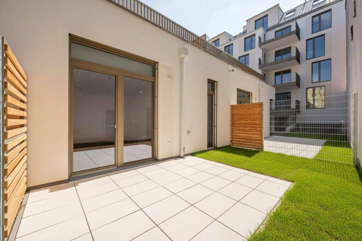 Sonnige Terrasse mit Kunstrasen und großen Fenstern, die viel Licht hereinlassen.