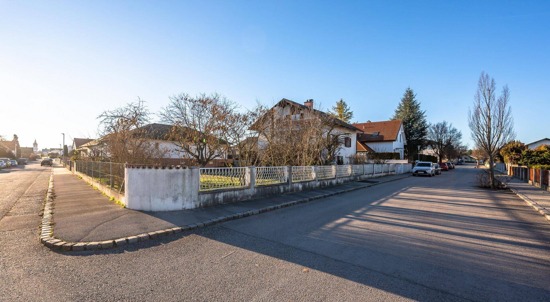 Weitläufige Ansicht einer ruhigen Wohnstraße mit Häusern und einem Eckgrundstück.