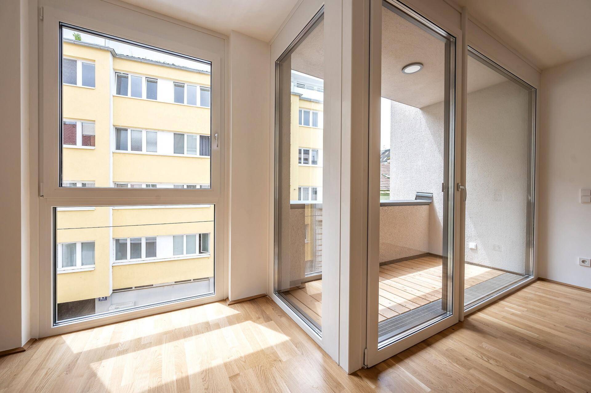 Detailansicht der großen Fenster und Balkontür, die den Raum mit natürlichem Licht füllen.