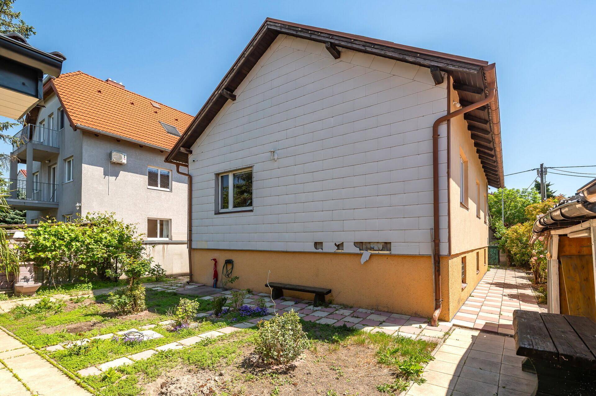 Seitenansicht des Hauses mit einfacher Fassade und einem kleinen Gartenbereich.