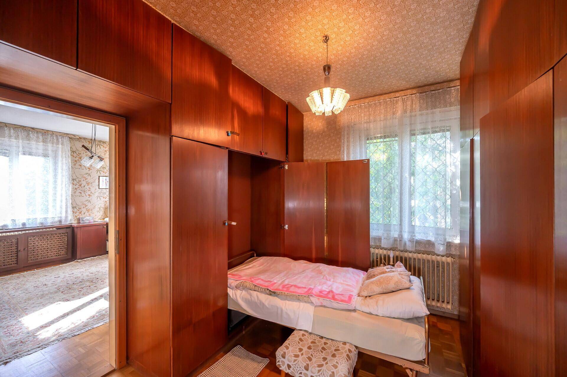 Schlafzimmer mit integrierten Holzschränken und einem ausklappbaren Bett, sehr funktional.