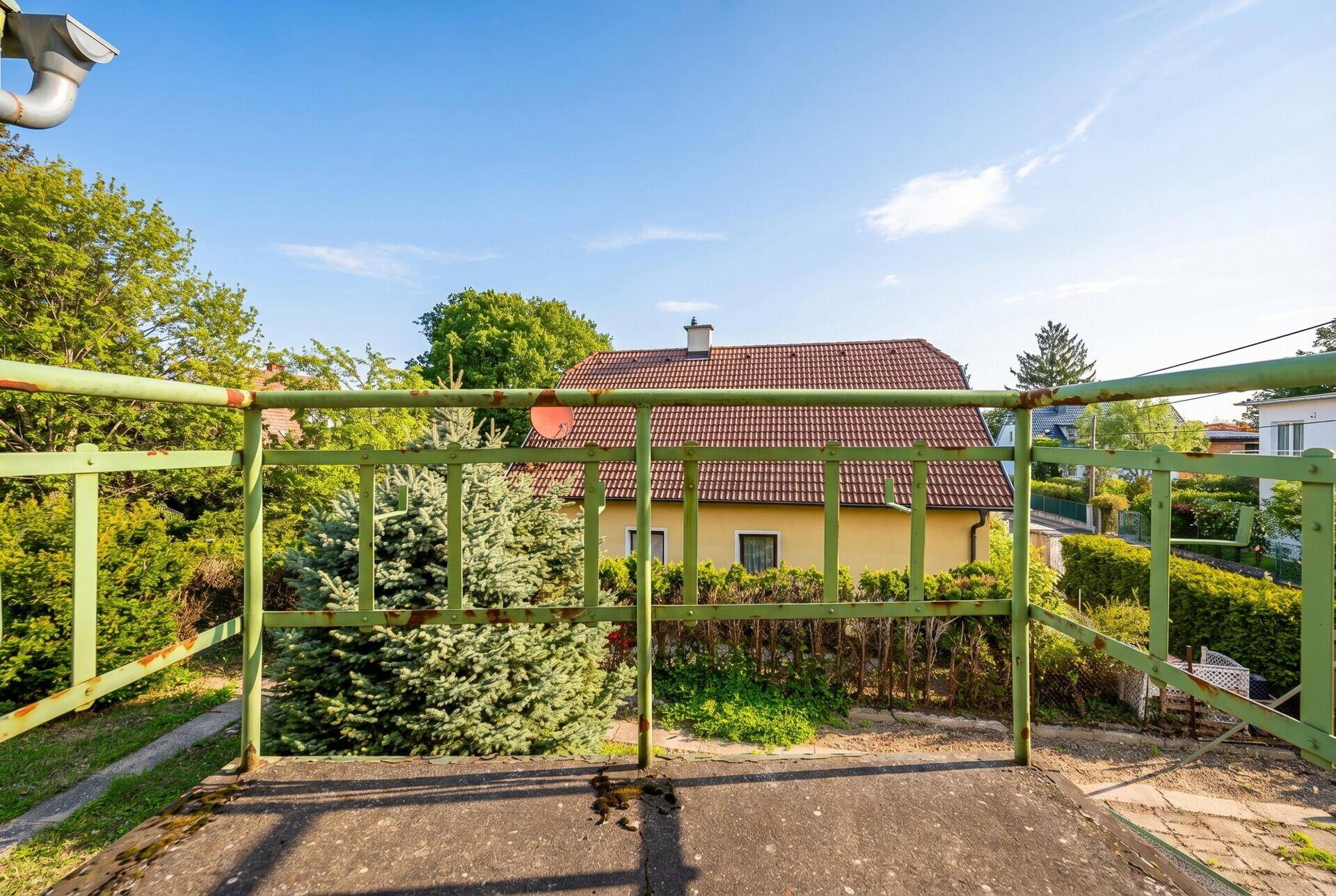 Blick vom Balkon auf die Nachbarschaft mit Häusern und viel Grün.