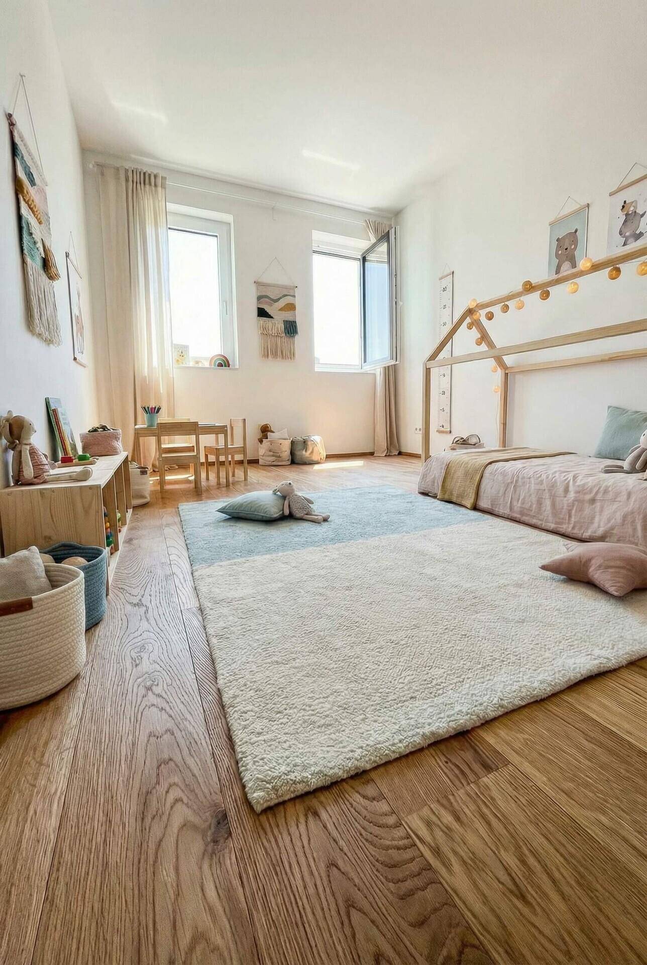 Helles Kinderzimmer mit Holzboden, einem Hausbett und kindgerechter Einrichtung.