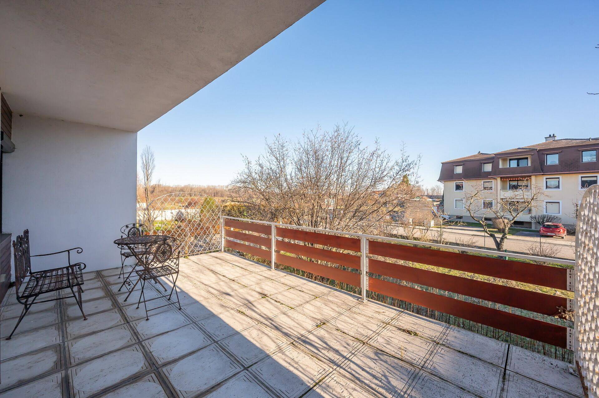 Großer gefliester Balkon mit Gartenmöbeln und weitem Blick auf die Umgebung.