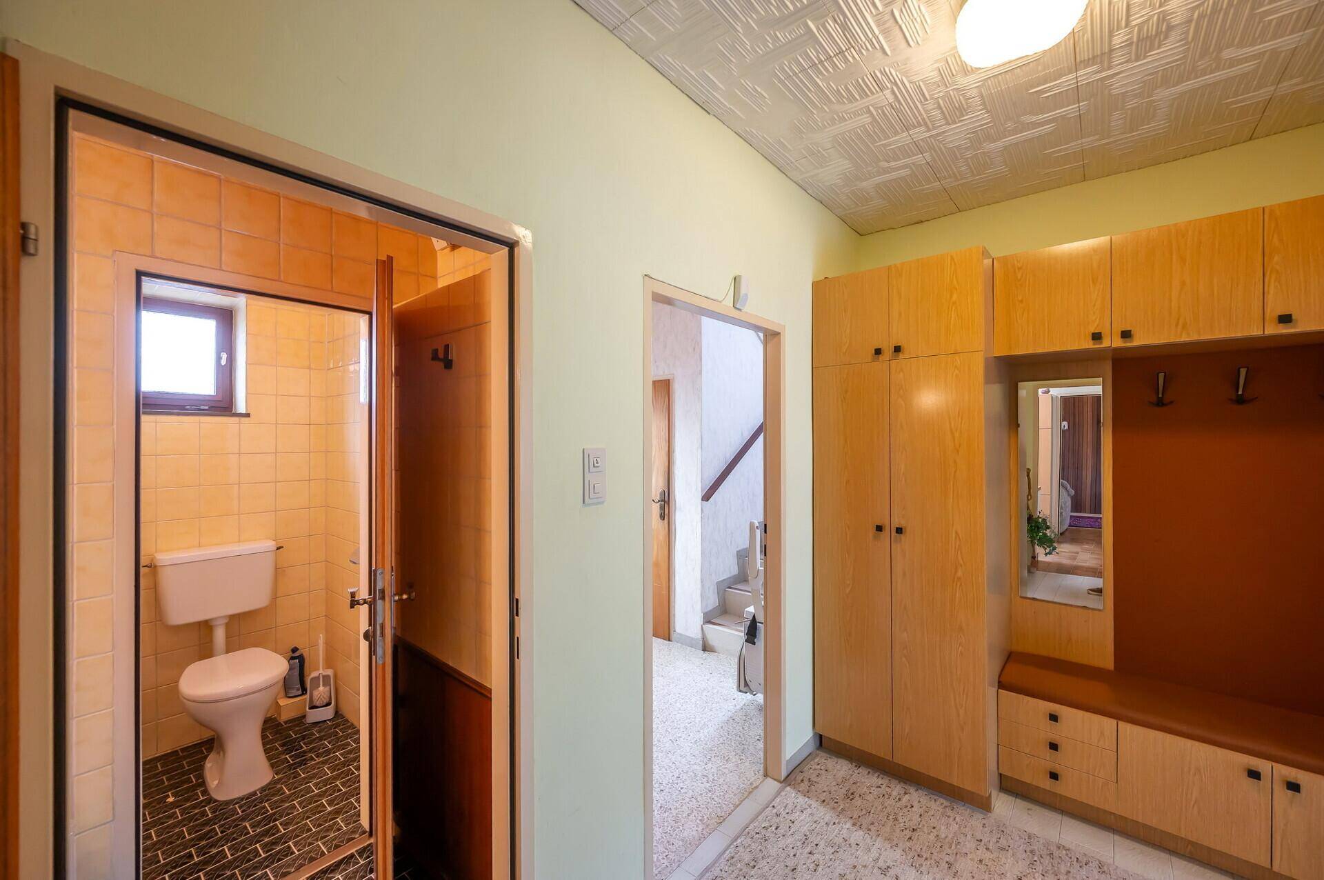 Heller Flur mit Einbauschränken und Zugang zu einem gefliesten Gäste-WC.