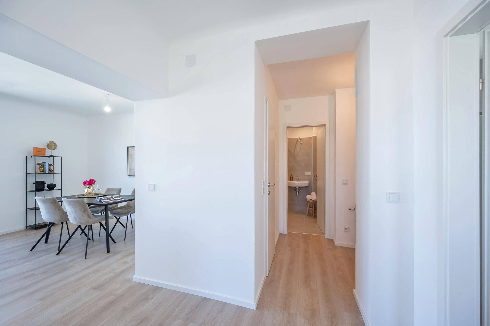 Heller Flur mit Zugang zum Badezimmer und offenem Blick in den Wohnbereich.