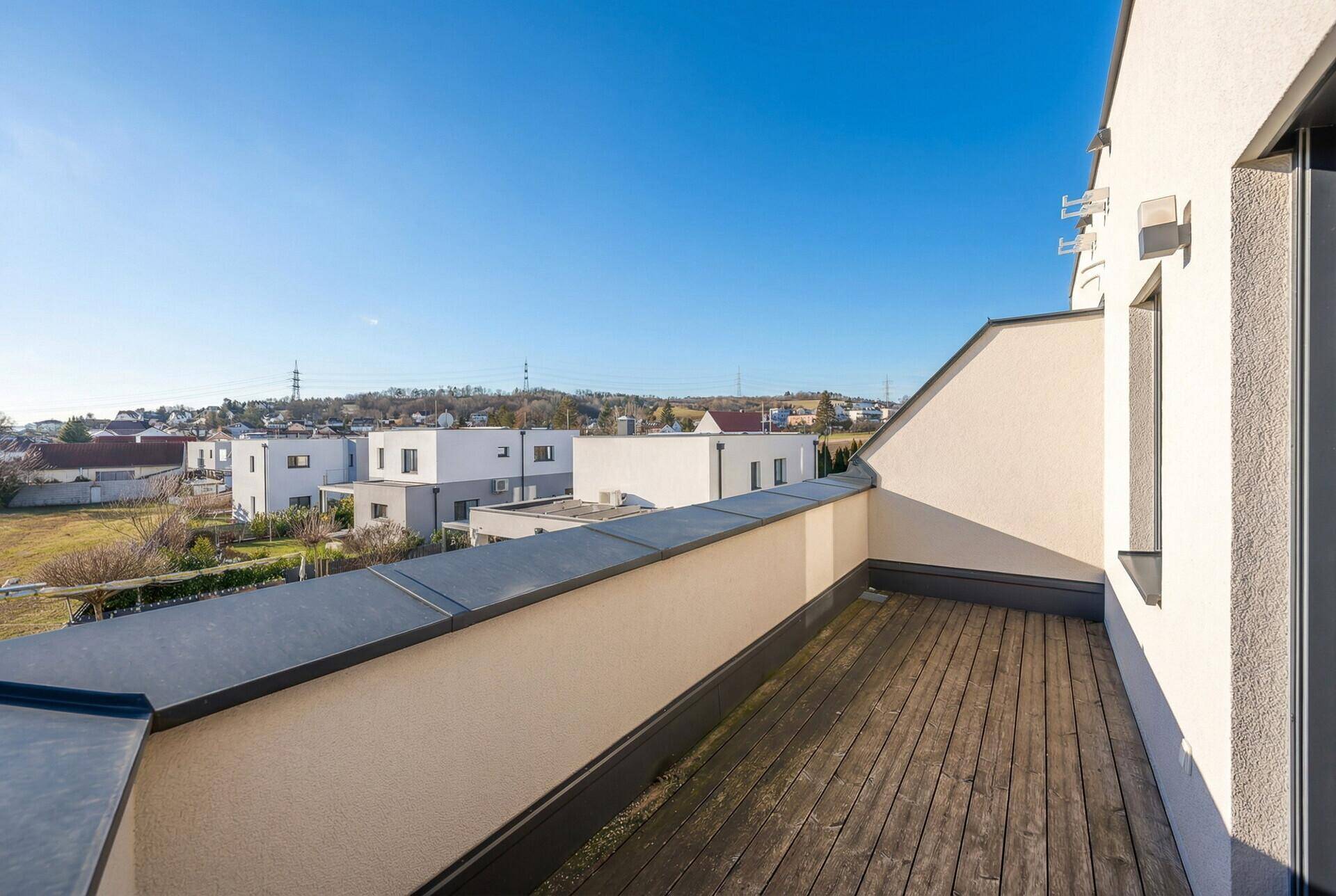 Geräumige Dachterrasse mit Holzboden und weitem Blick über die Umgebung.