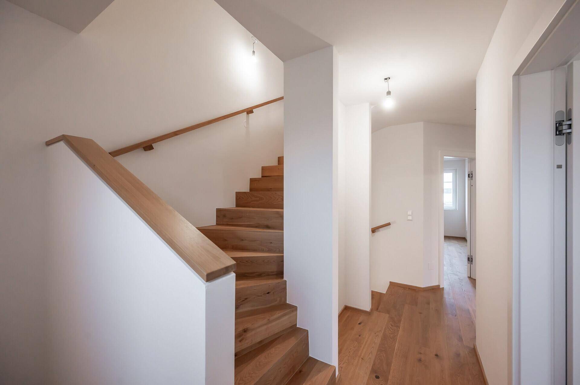 Holztreppe führt in den oberen Flur mit hellem Holzboden.