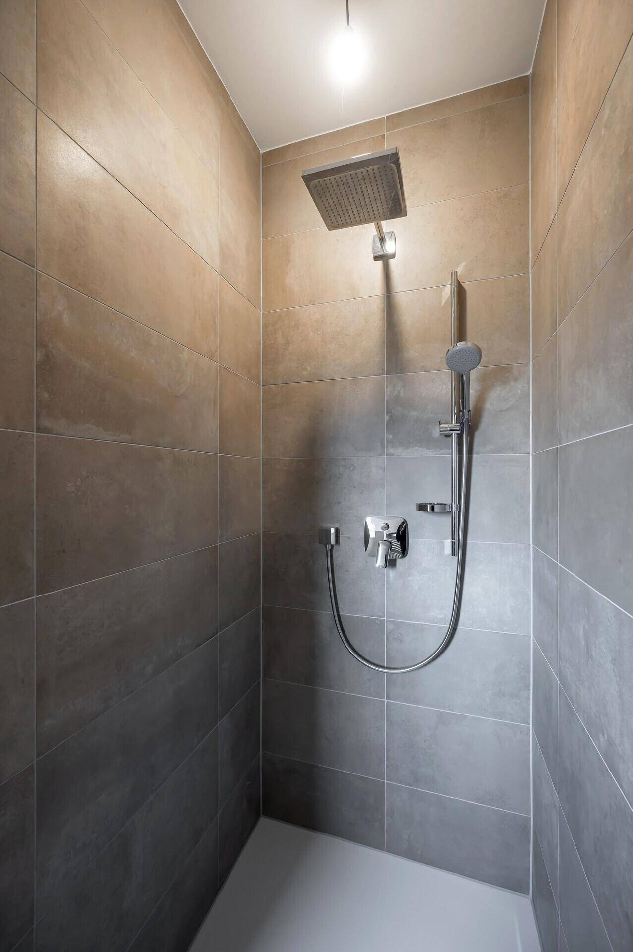 Moderne Duschkabine mit Regendusche und großformatigen Fliesen.