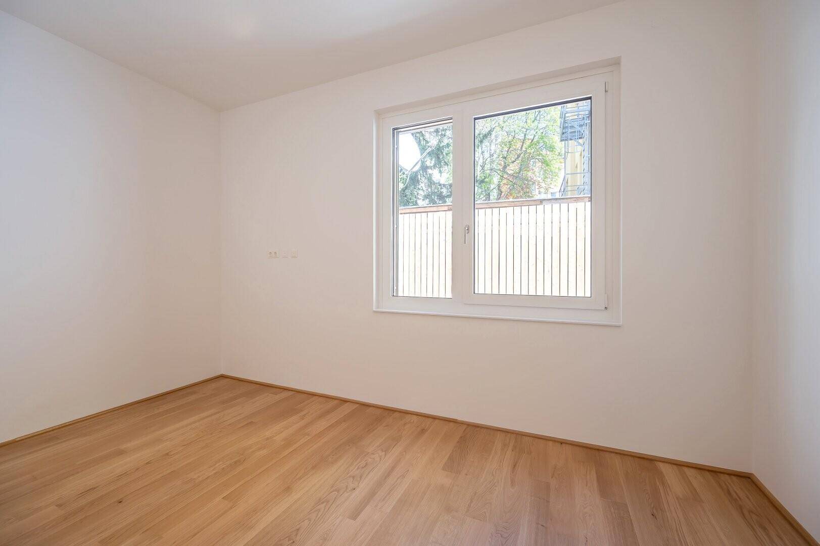 Heller Raum mit Holzboden und Fenster, ideal als Schlaf- oder Arbeitszimmer.