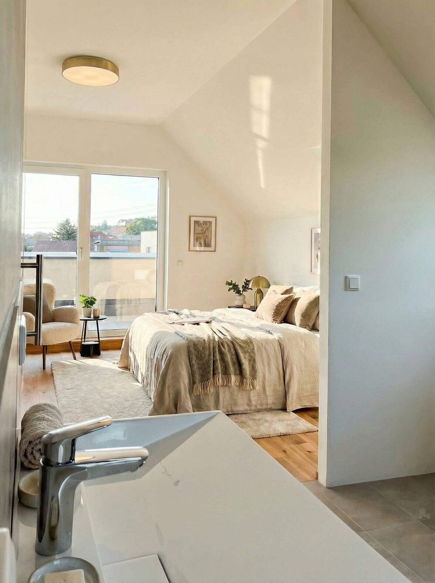 Schlafzimmer im Dachgeschoss mit Dachschräge, Holzboden und Zugang zu einem Balkon.