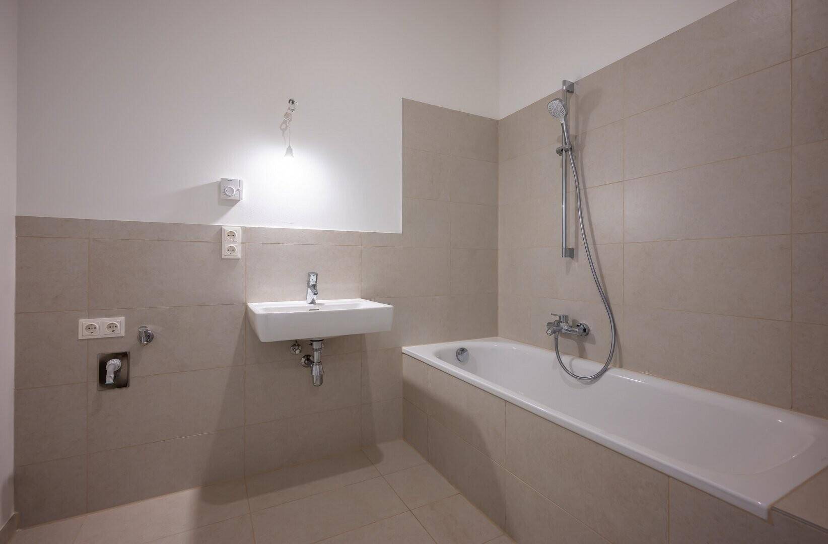 Modernes Badezimmer mit Badewanne, Waschbecken und hellen Fliesen.