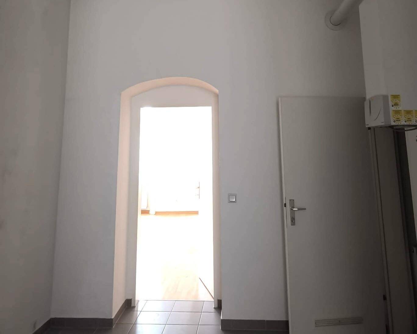 Heller Durchgang mit Rundbogen führt von einem gefliesten Bereich in einen weiteren Raum.