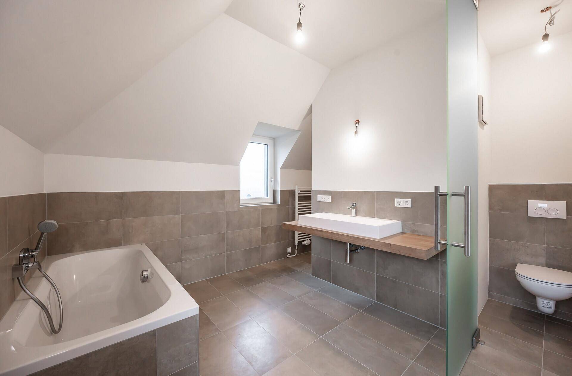 Großes Badezimmer im Dachgeschoss mit Badewanne, Dusche und Einzelwaschbecken.