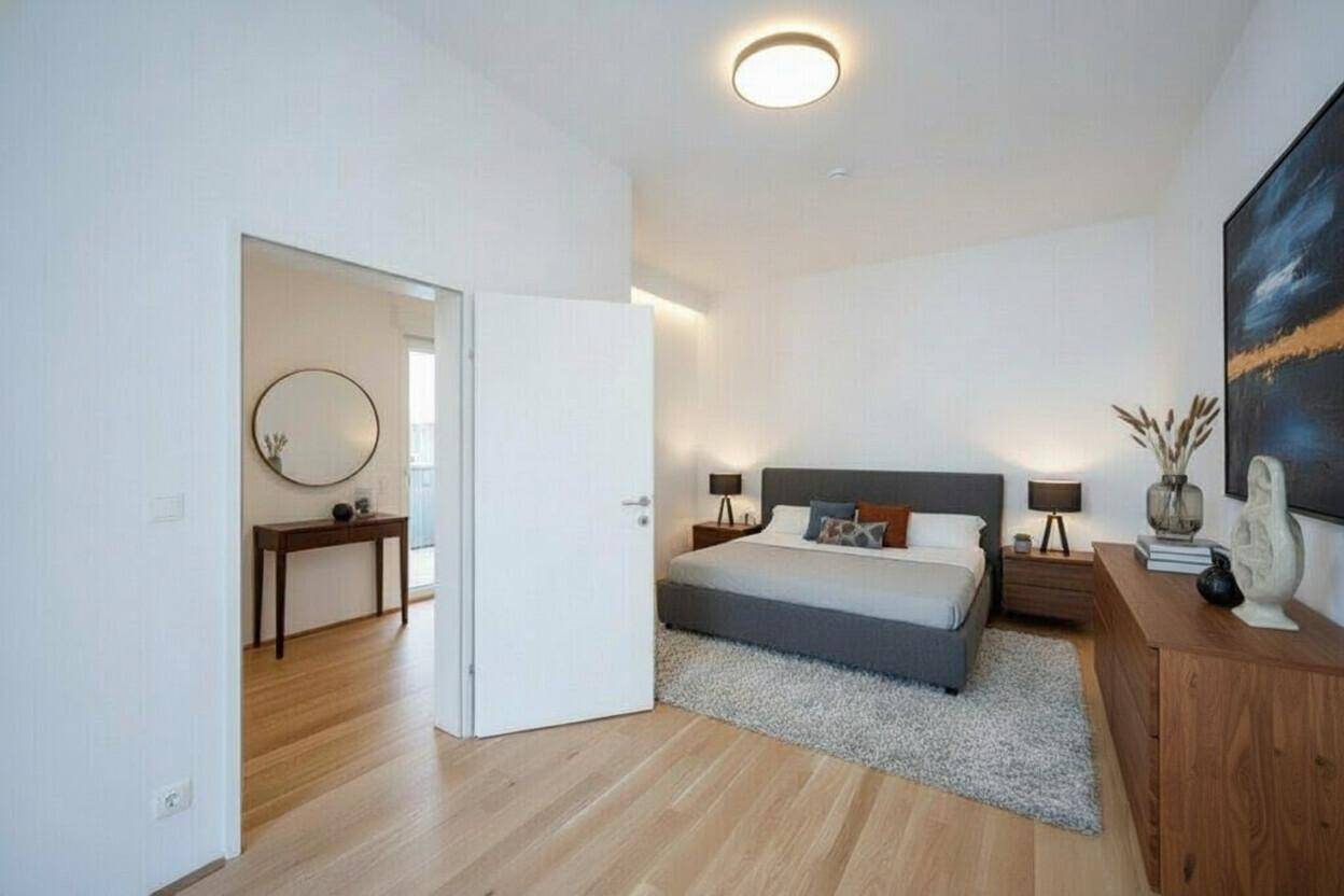 Modernes Schlafzimmer mit Holzboden, Doppelbett und Zugang zu einem weiteren Raum.