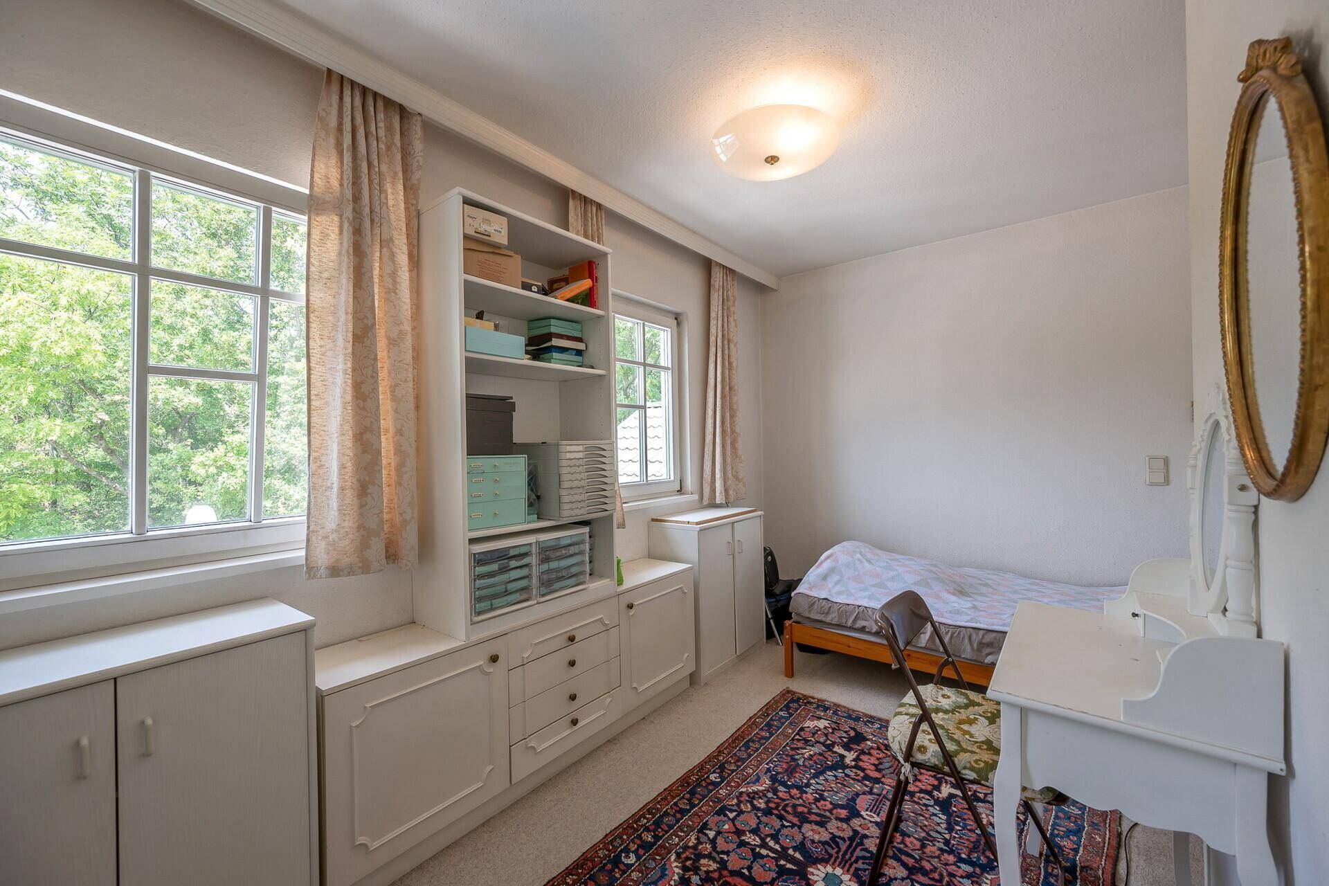 Gemütliches Schlafzimmer mit Einzelbett, Schreibtisch und integrierten Schränken.