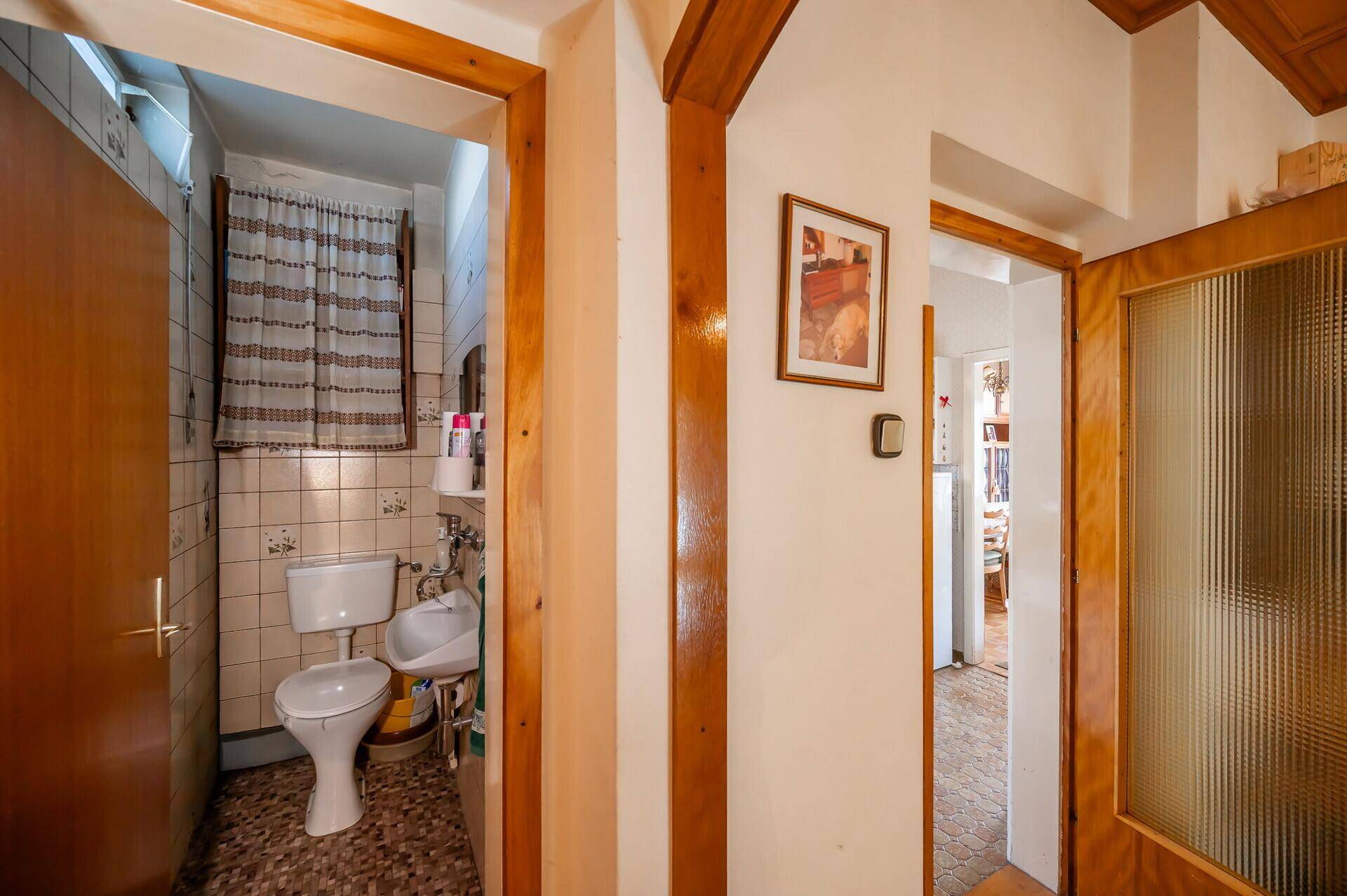 Kleines Gäste-WC mit gefliesten Wänden und Boden, ausgestattet mit Toilette und Waschbecken.