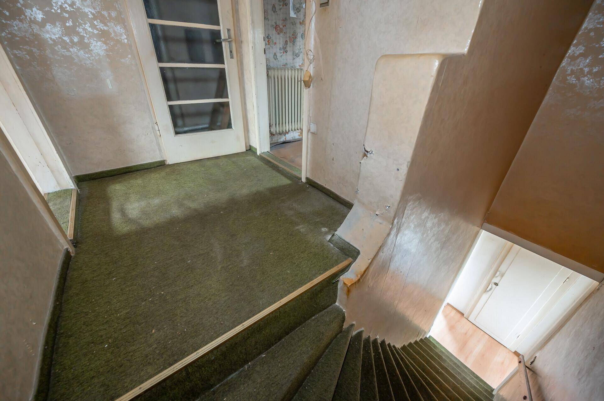 Treppenabsatz mit grünem Teppichboden und Blick auf die untere Etage.
