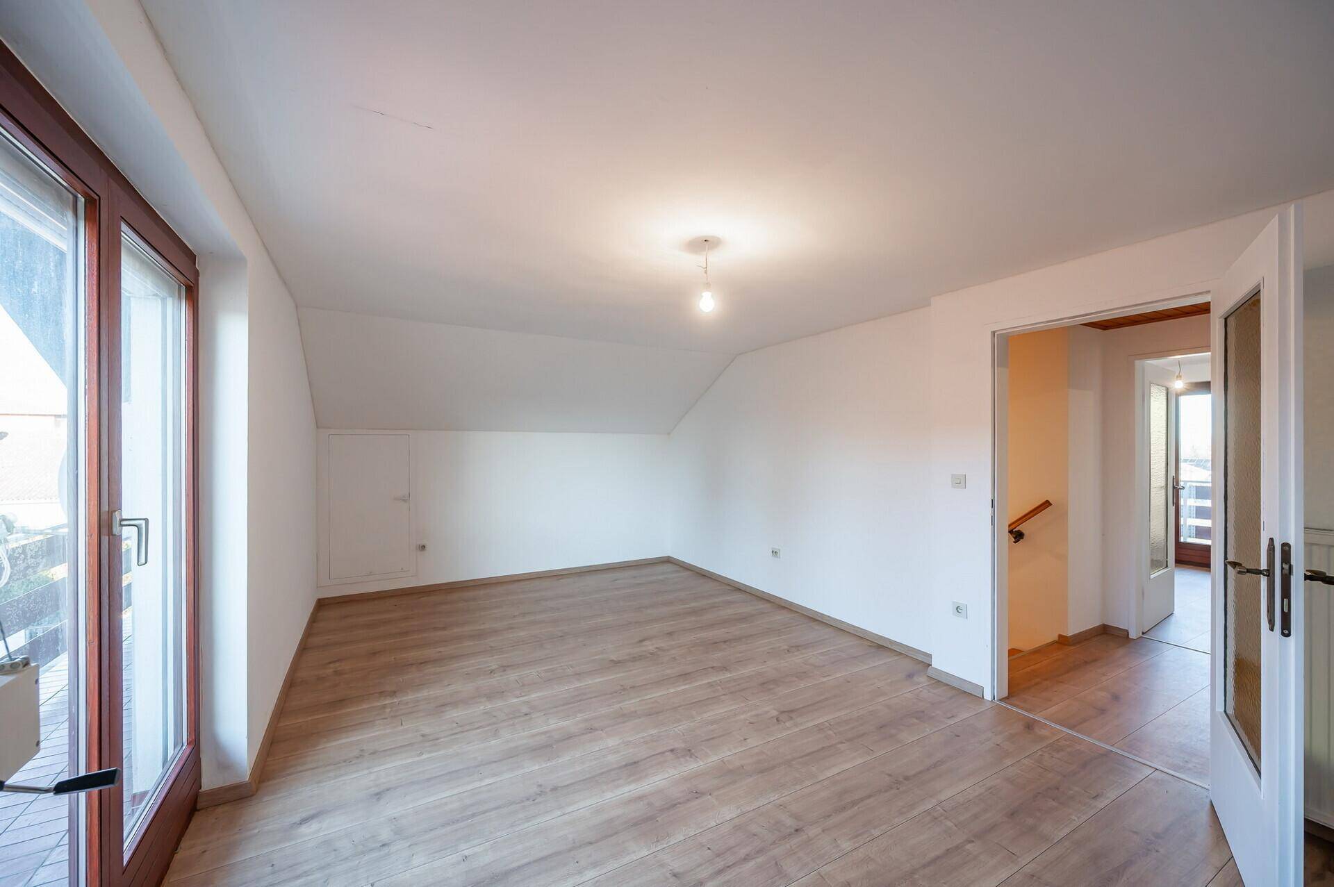 Geräumiges Dachgeschosszimmer mit Laminatboden und Balkontür, bereit zur individuellen Gestaltung.