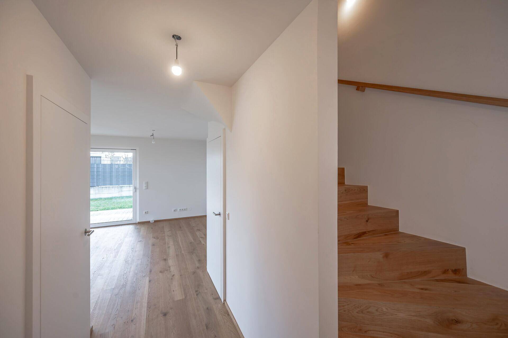 Geräumiger Eingangsbereich mit Holztreppe und Eichenparkett, der die Etagen stilvoll verbindet.