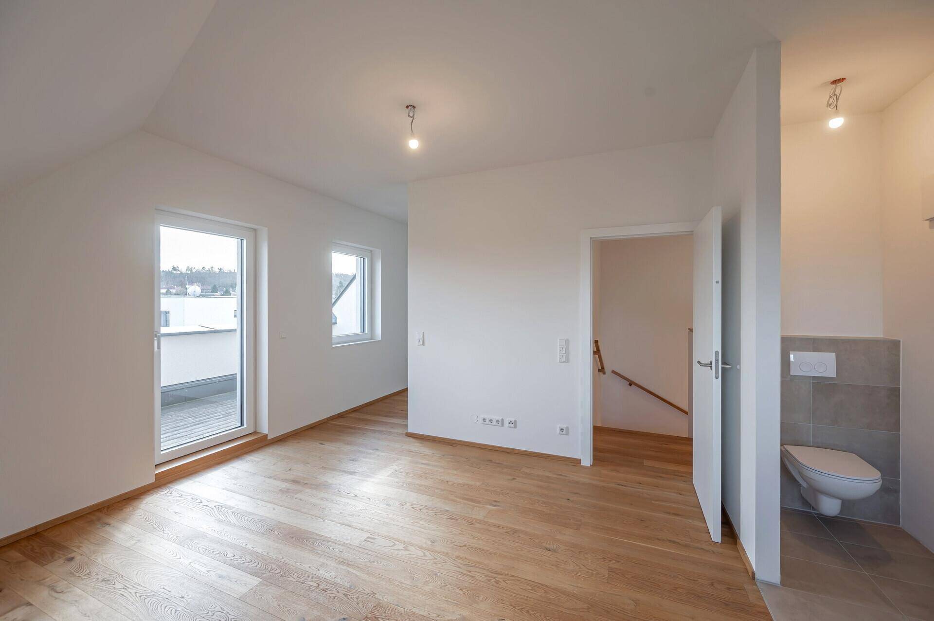 Geräumiges Schlafzimmer im Dachgeschoss mit Holzboden und direktem Zugang zum Badezimmer.