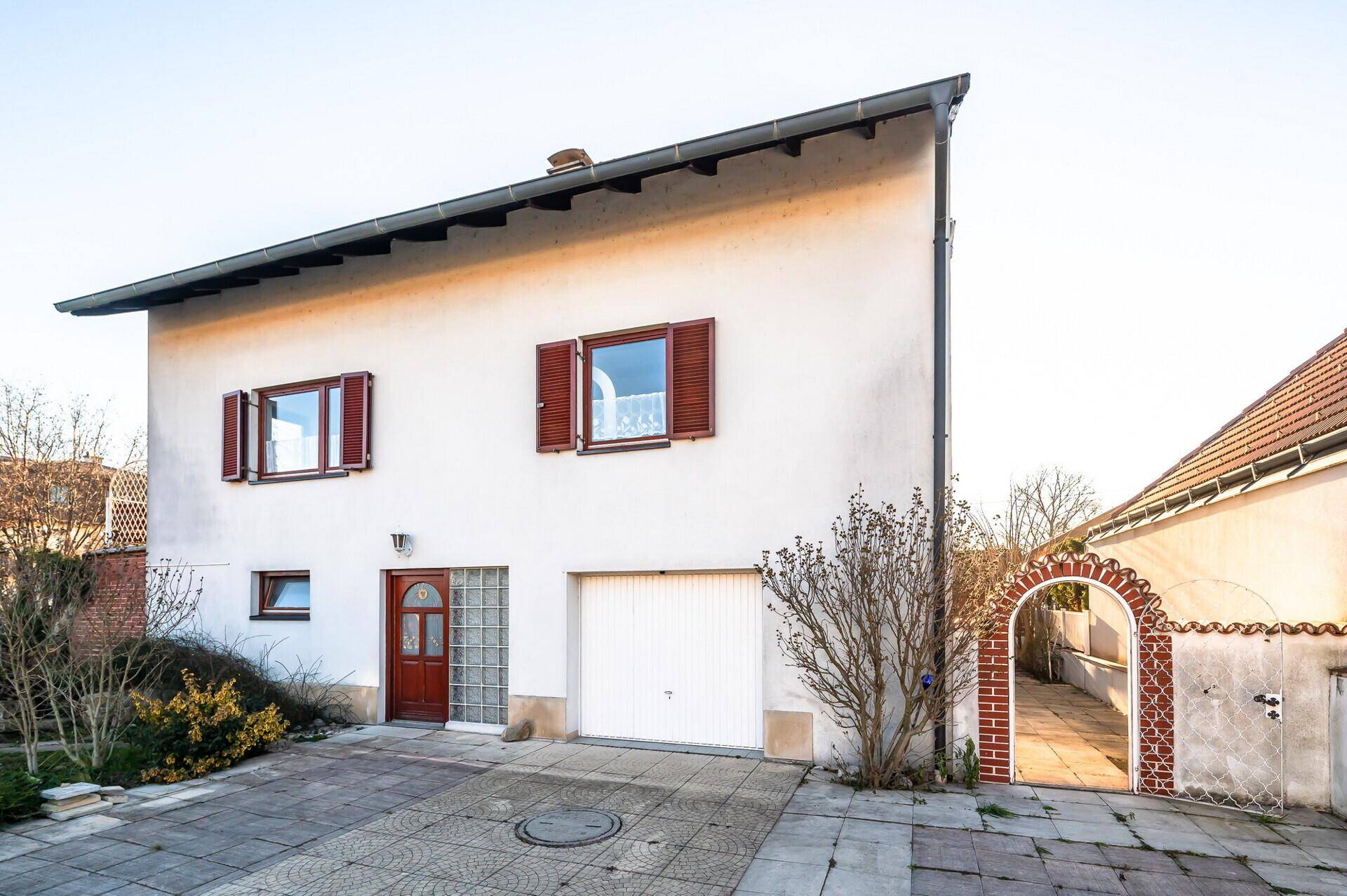 Vorderansicht des Hauses mit Garage, Haupteingang und gepflasterter Auffahrt.