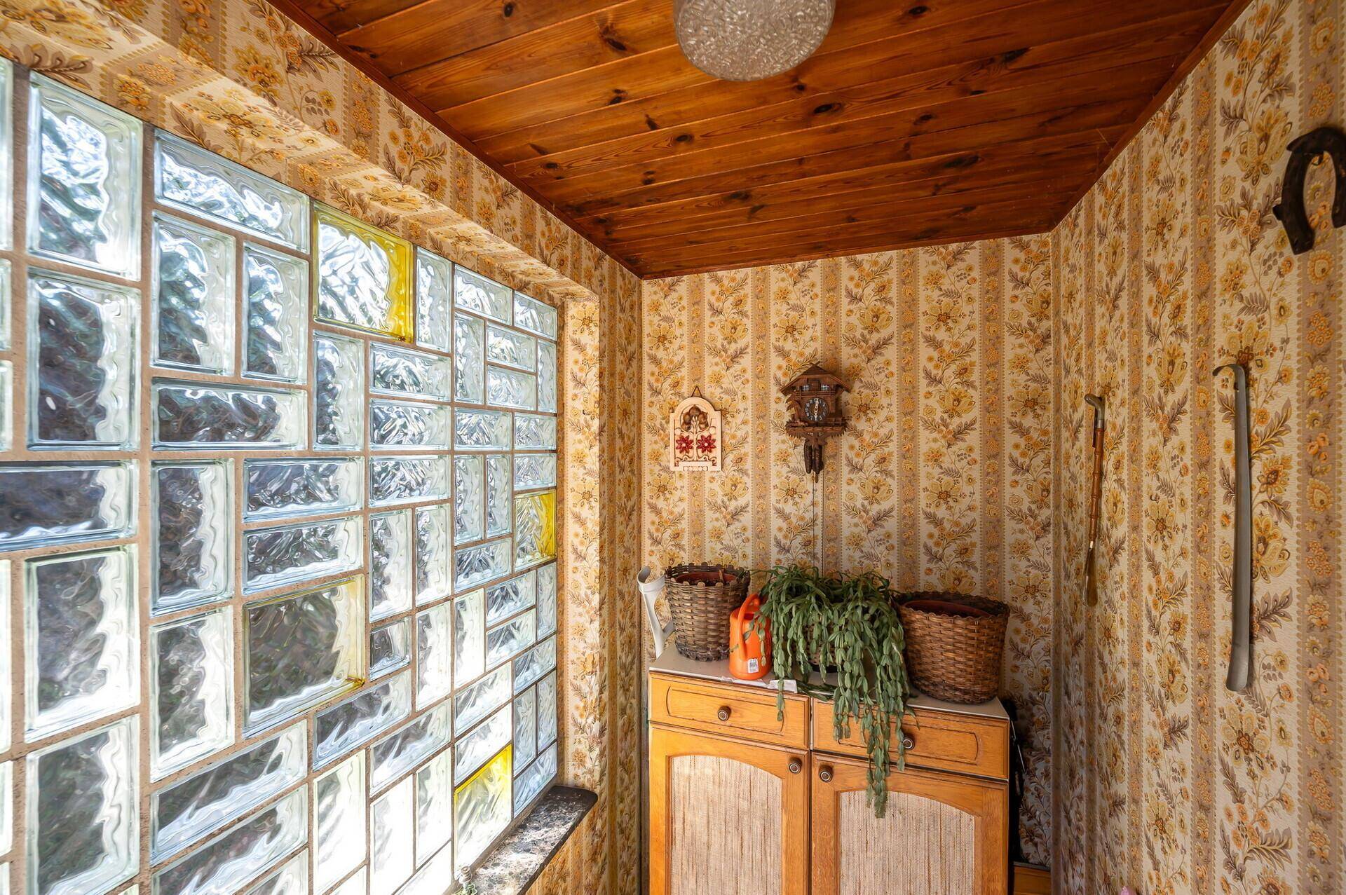 Kleiner Eingangsbereich mit Glasbausteinwand, Holzdecke und gemusterter Tapete im Vintage-Stil.