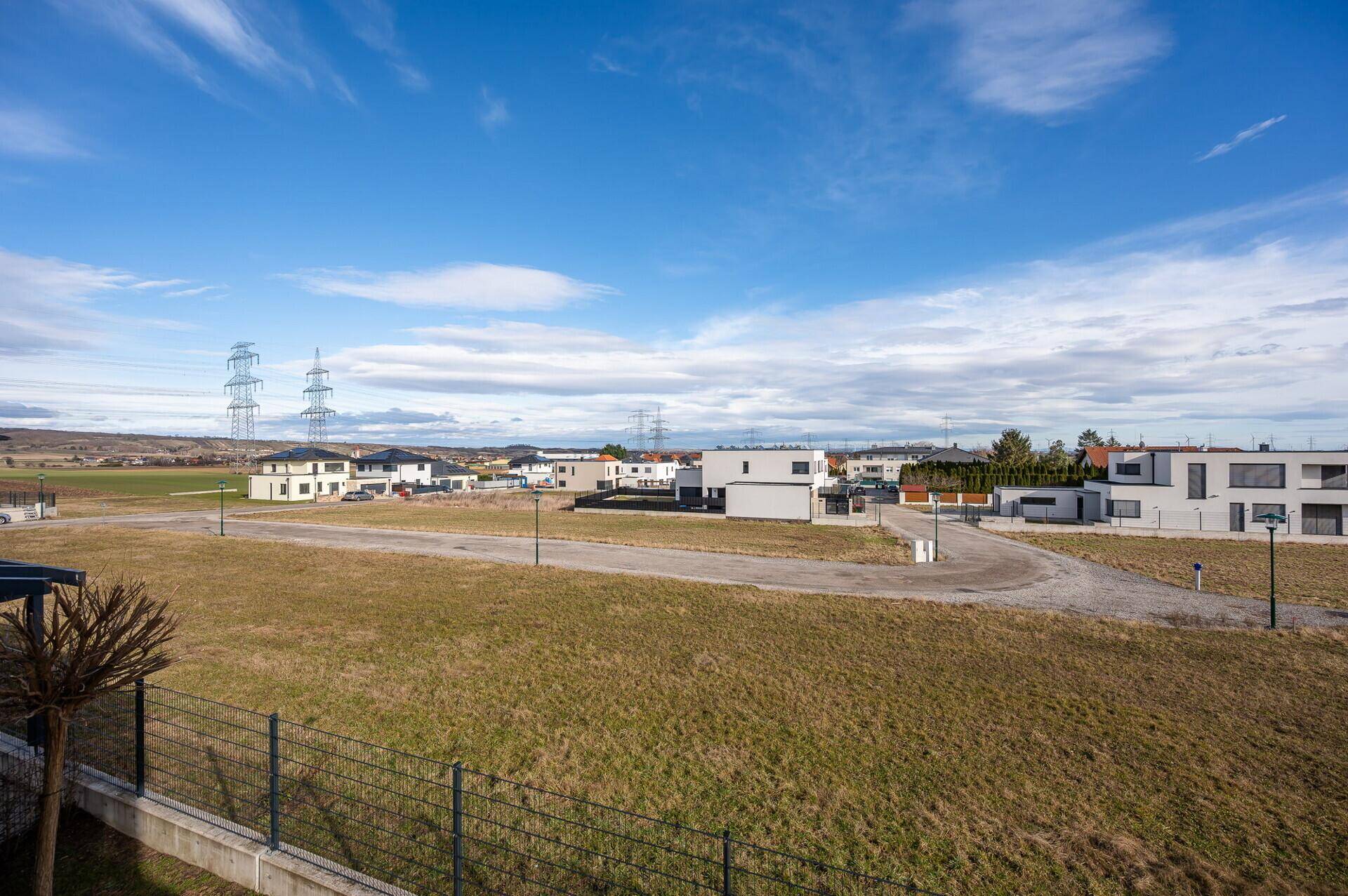 Weitläufiger Blick über die ländliche Umgebung mit neuen Wohnhäusern und Strommasten.
