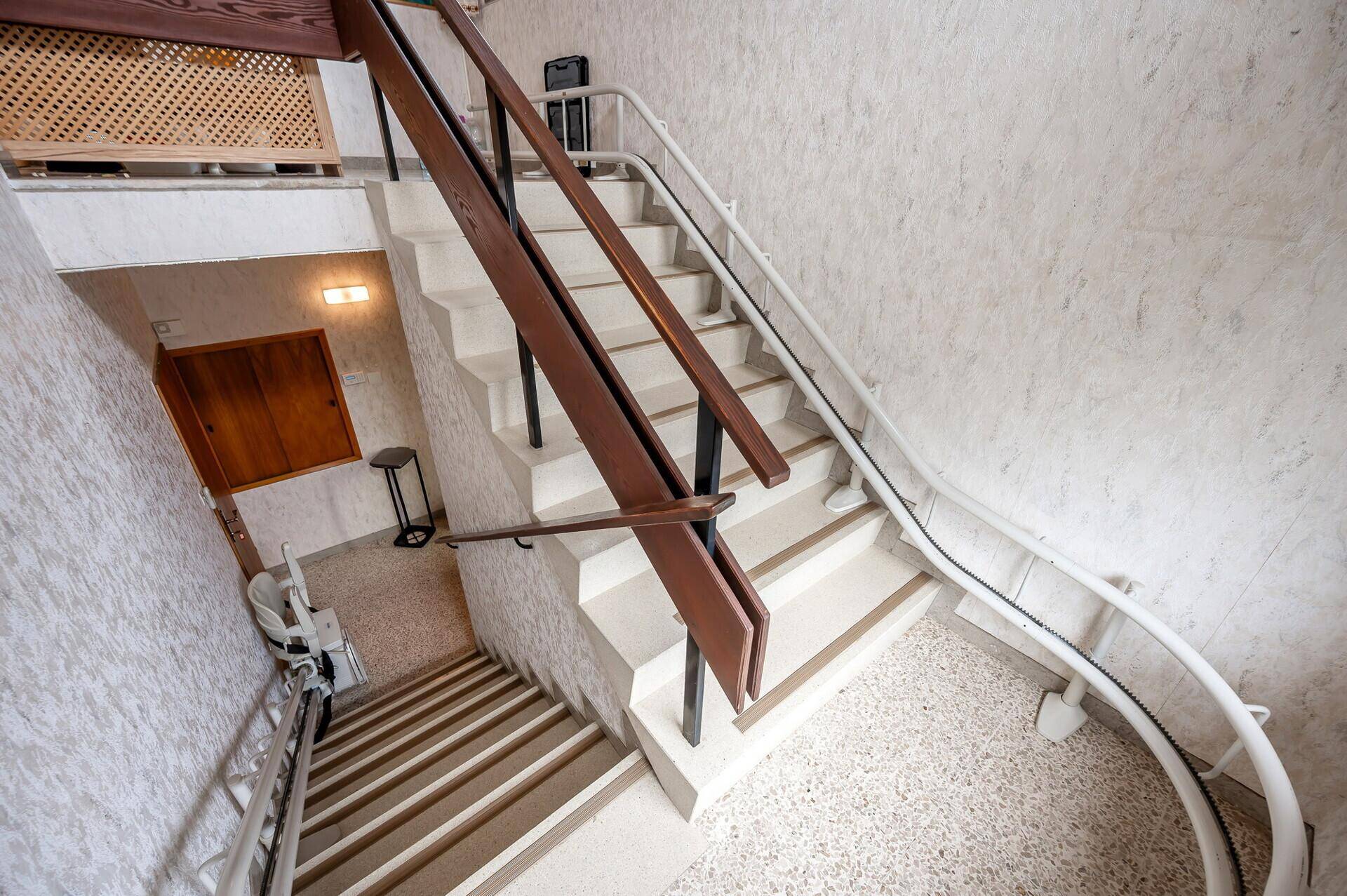 Blick von oben auf die Treppe mit dem installierten Treppenlift und Holzgeländer.