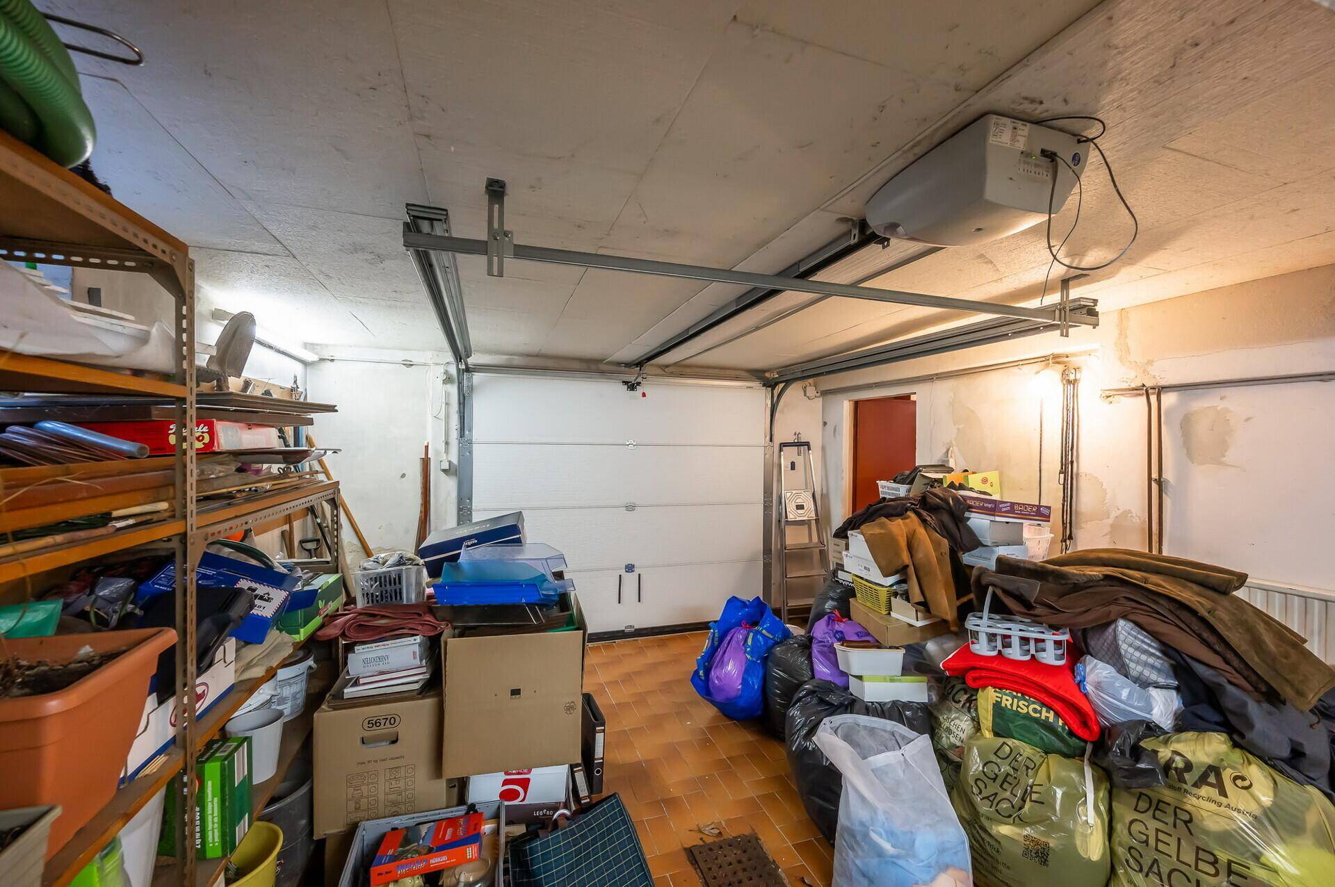 Geräumige Garage mit automatischem Tor, Fliesenboden und viel Stauraum.
