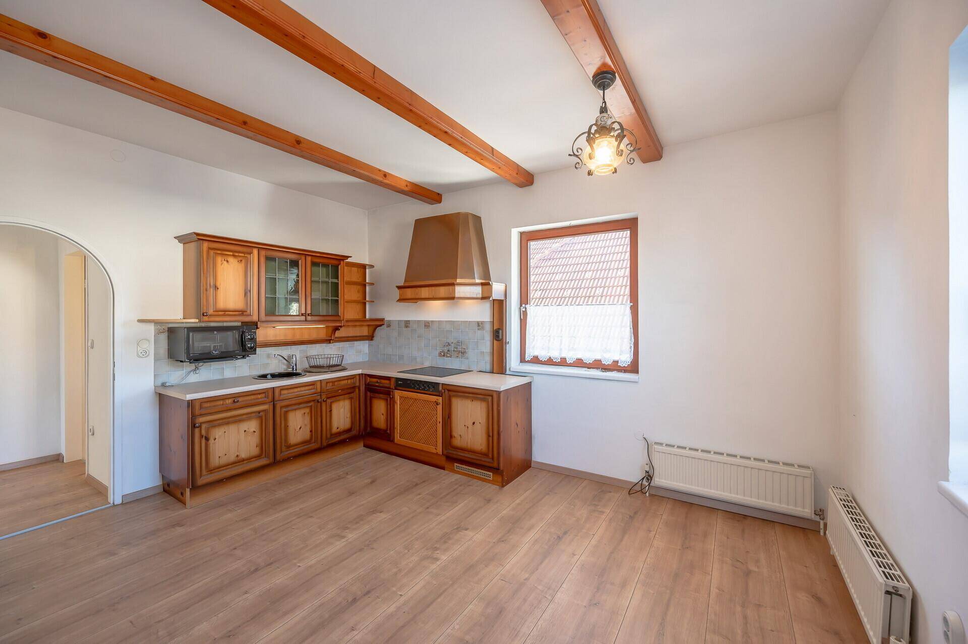 Traditionelle Holzküche mit Einbauschränken, Mikrowelle und rustikalen Deckenbalken.
