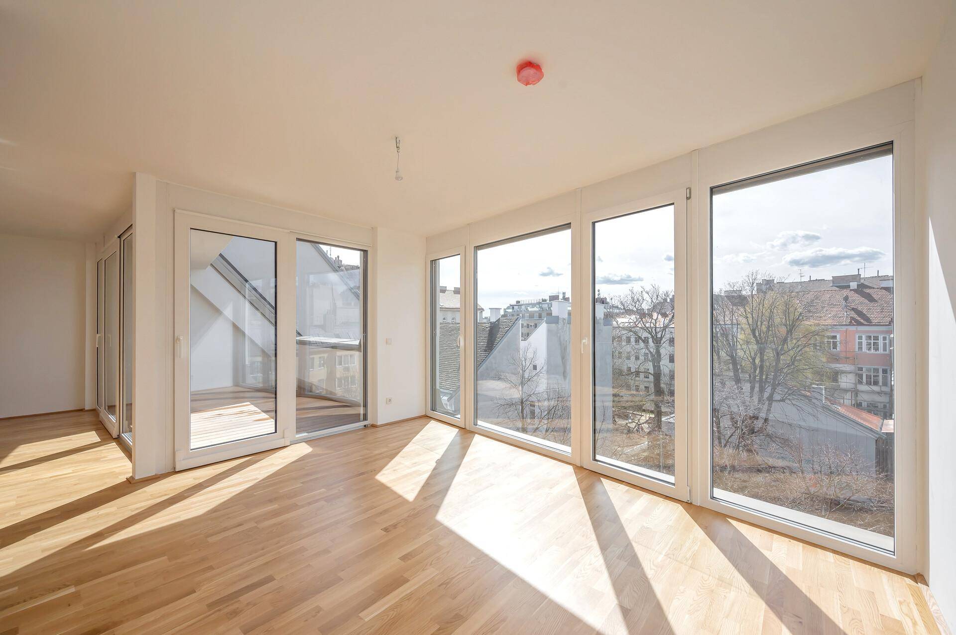 Lichtdurchfluteter Wohnraum mit Holzboden und großen Fenstern, die einen weiten Stadtblick bieten.