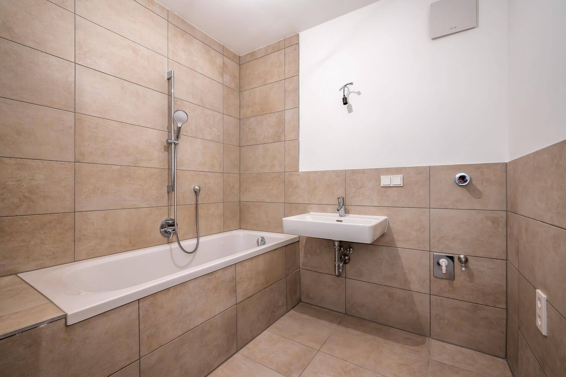 Modernes Badezimmer mit beigefarbenen Fliesen, Badewanne und Waschbecken.