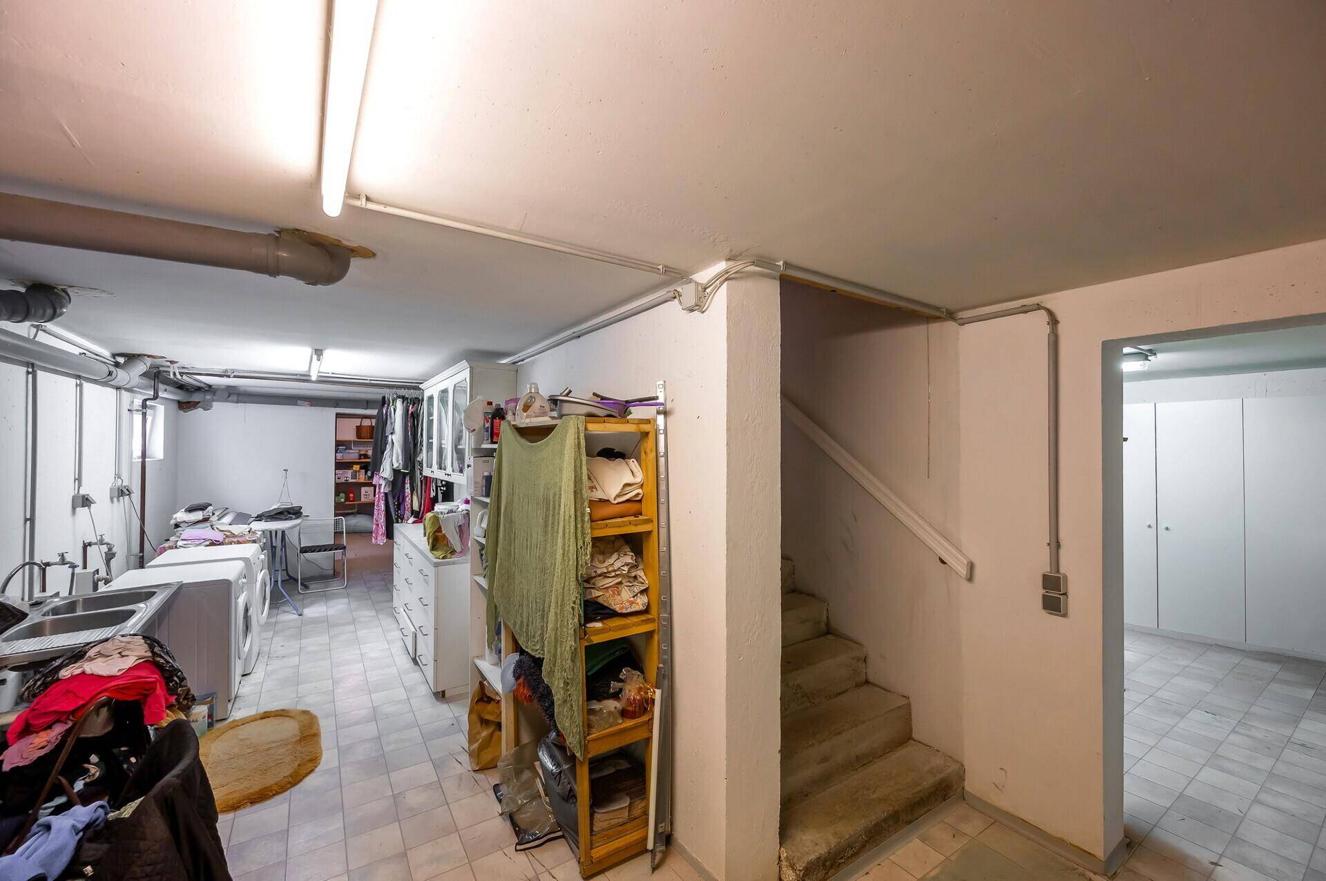 Waschküche im Keller mit Waschmaschinen und Stauraum.