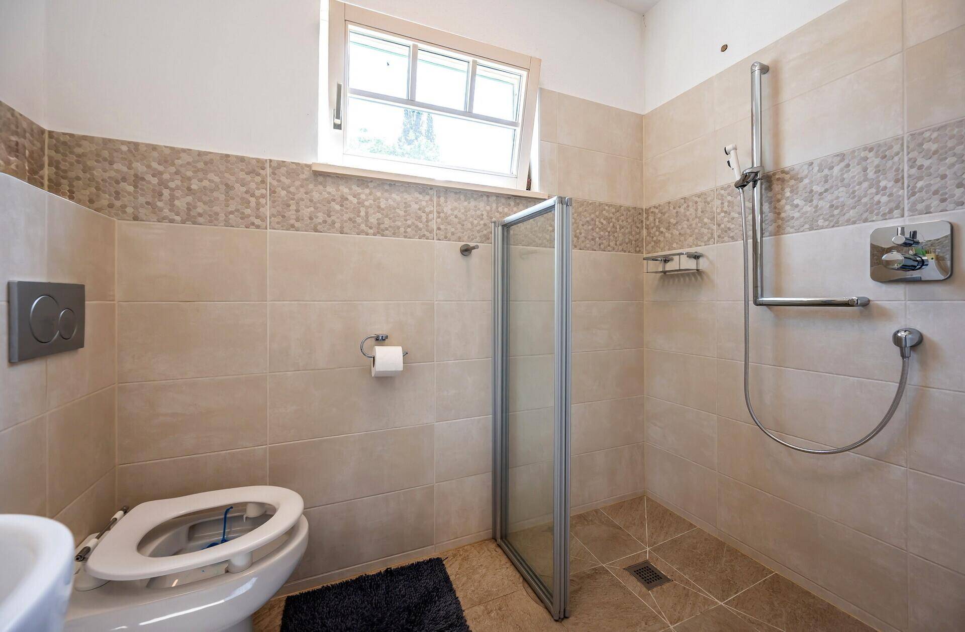 Modernes Badezimmer mit Dusche, Wand-WC und beigefarbenen Fliesen.