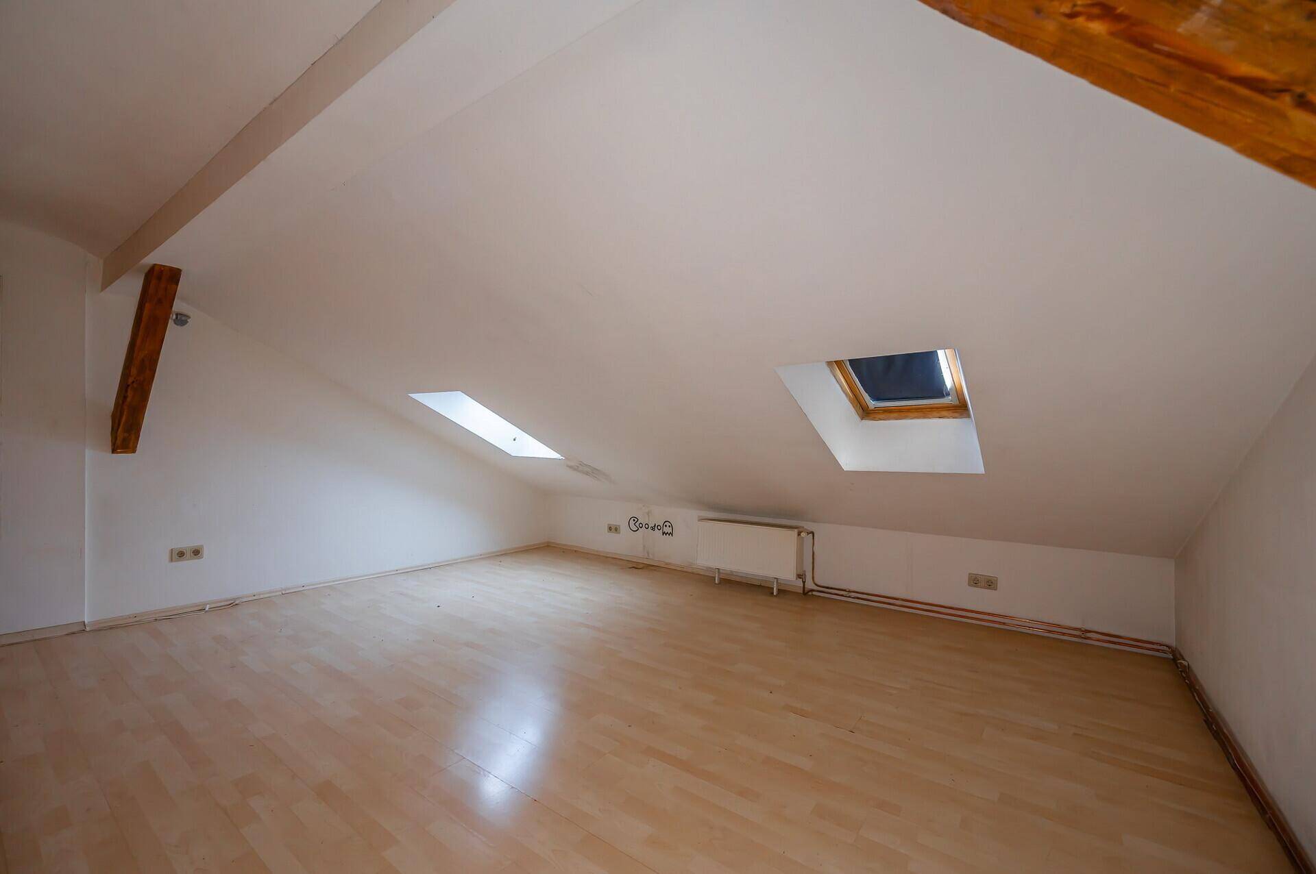 Dachgeschosszimmer mit Laminatboden, Dachschrägen und Dachfenstern, hell und geräumig.