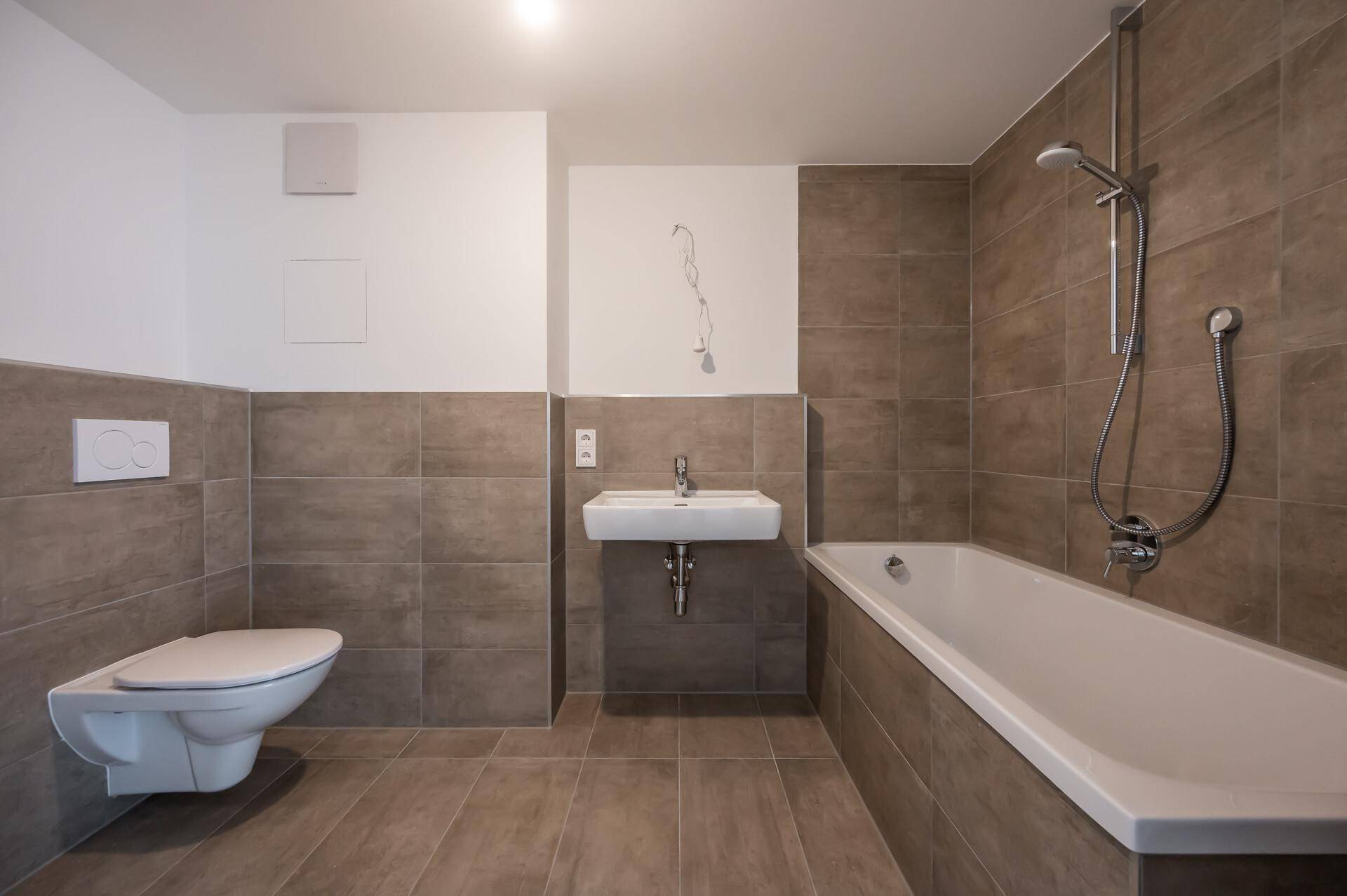 Modernes Badezimmer mit braunen Fliesen, Badewanne und wandhängendem WC.