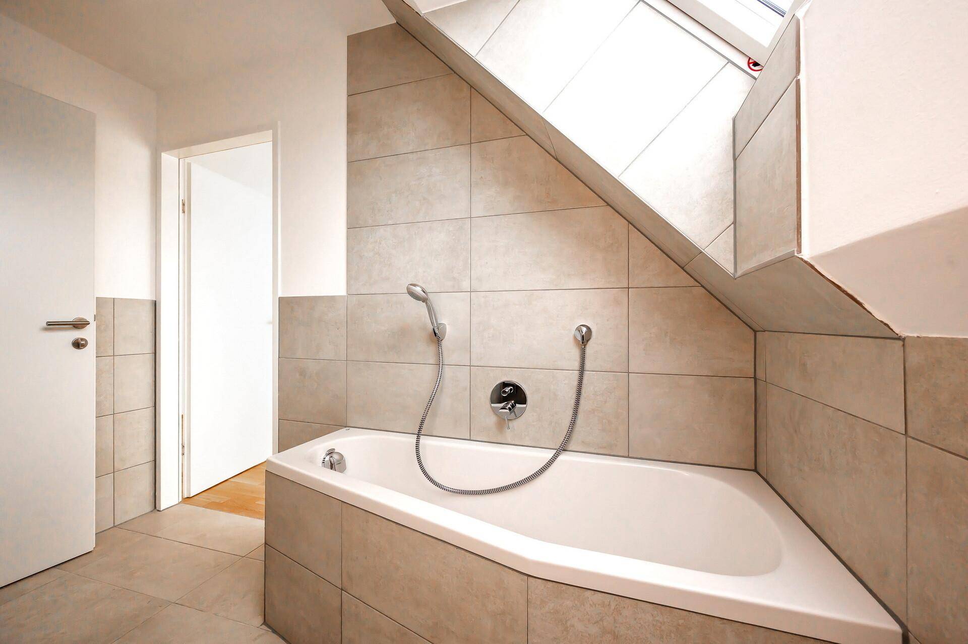 Helles Badezimmer mit beigefarbenen Fliesen und einer praktischen Eckbadewanne mit Duschfunktion.