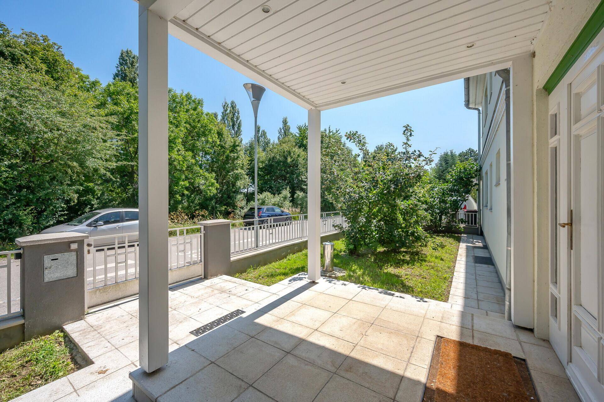 Überdachter Eingangsbereich des Hauses mit Blick auf die Straße und den Vorgarten.