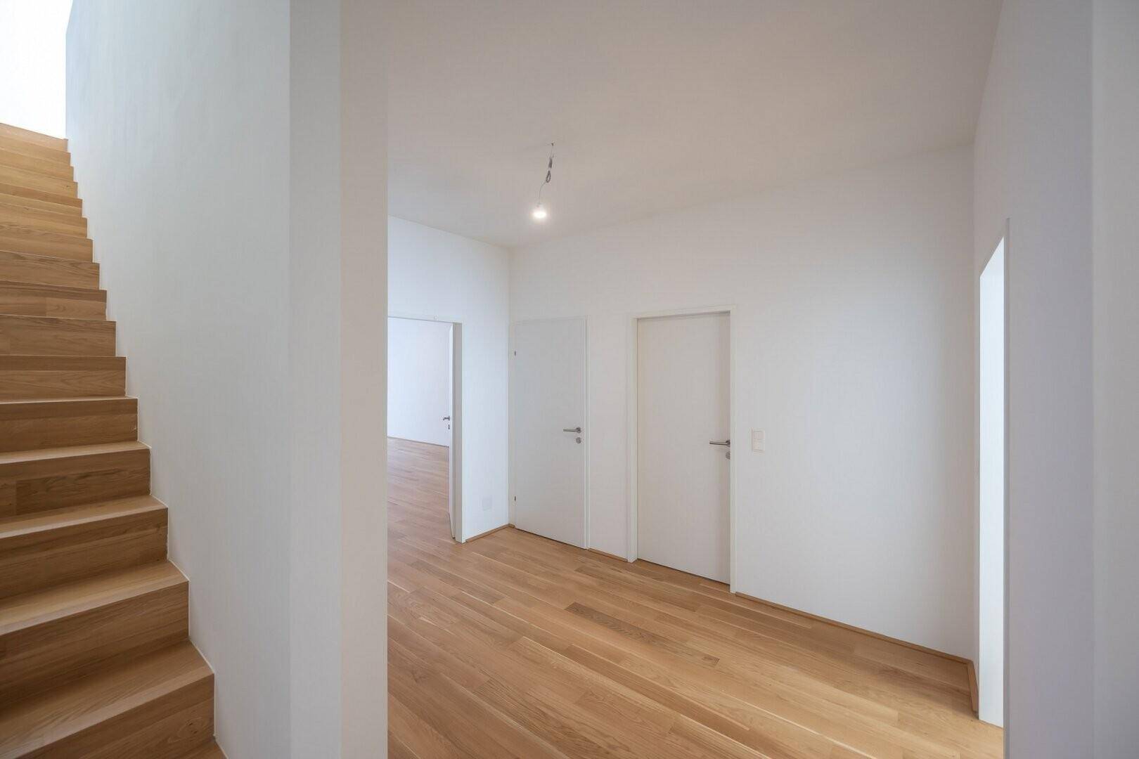 Geräumiger Flur mit hellem Holzboden und Zugang zu verschiedenen Zimmern.